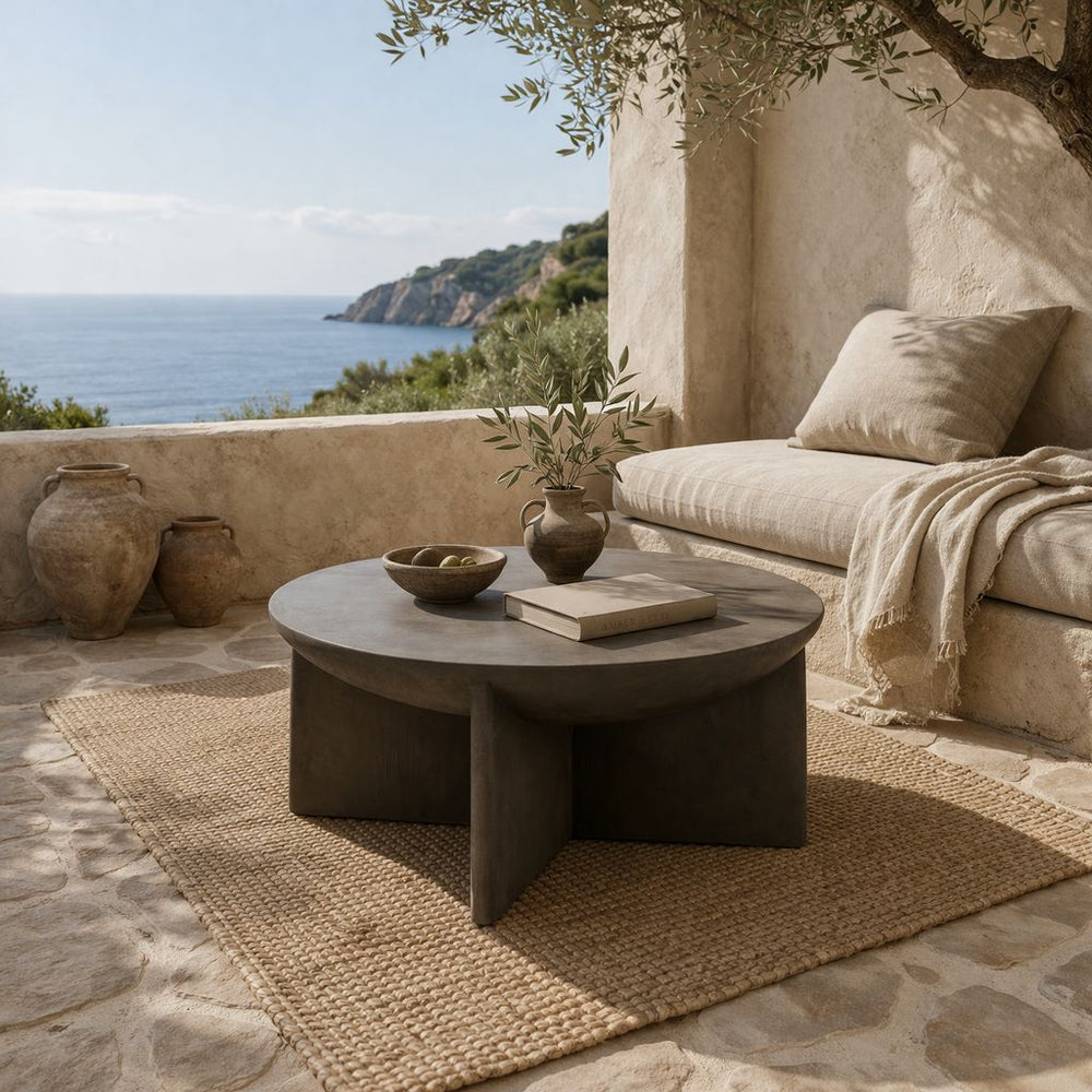 Axel round coffee table in pebble micro-cement on Mediterranean terrace with ocean view