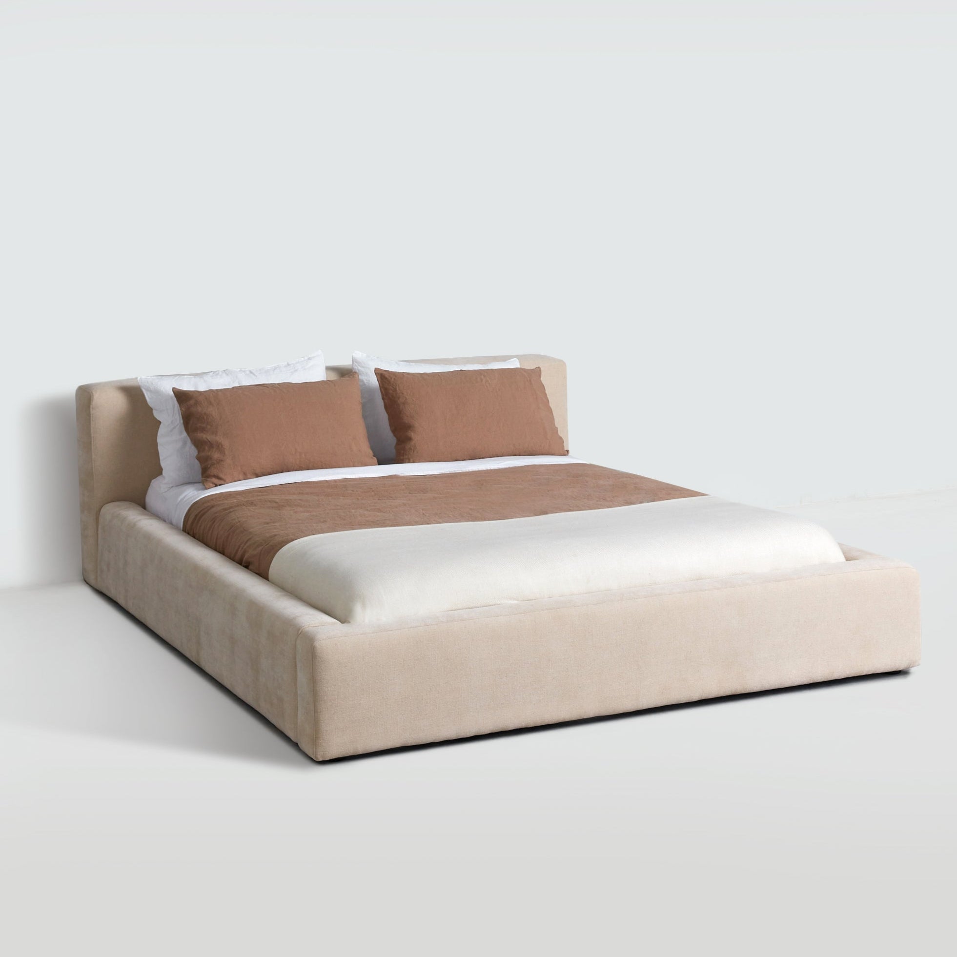 Cosmos upholstered bed in Oatmeal fabric, three-quarter angle highlighting soft edges and platform frame. Cosmos upholstered bed in Oatmeal fabric, three-quarter angle highlighting soft edges and platform frame.
