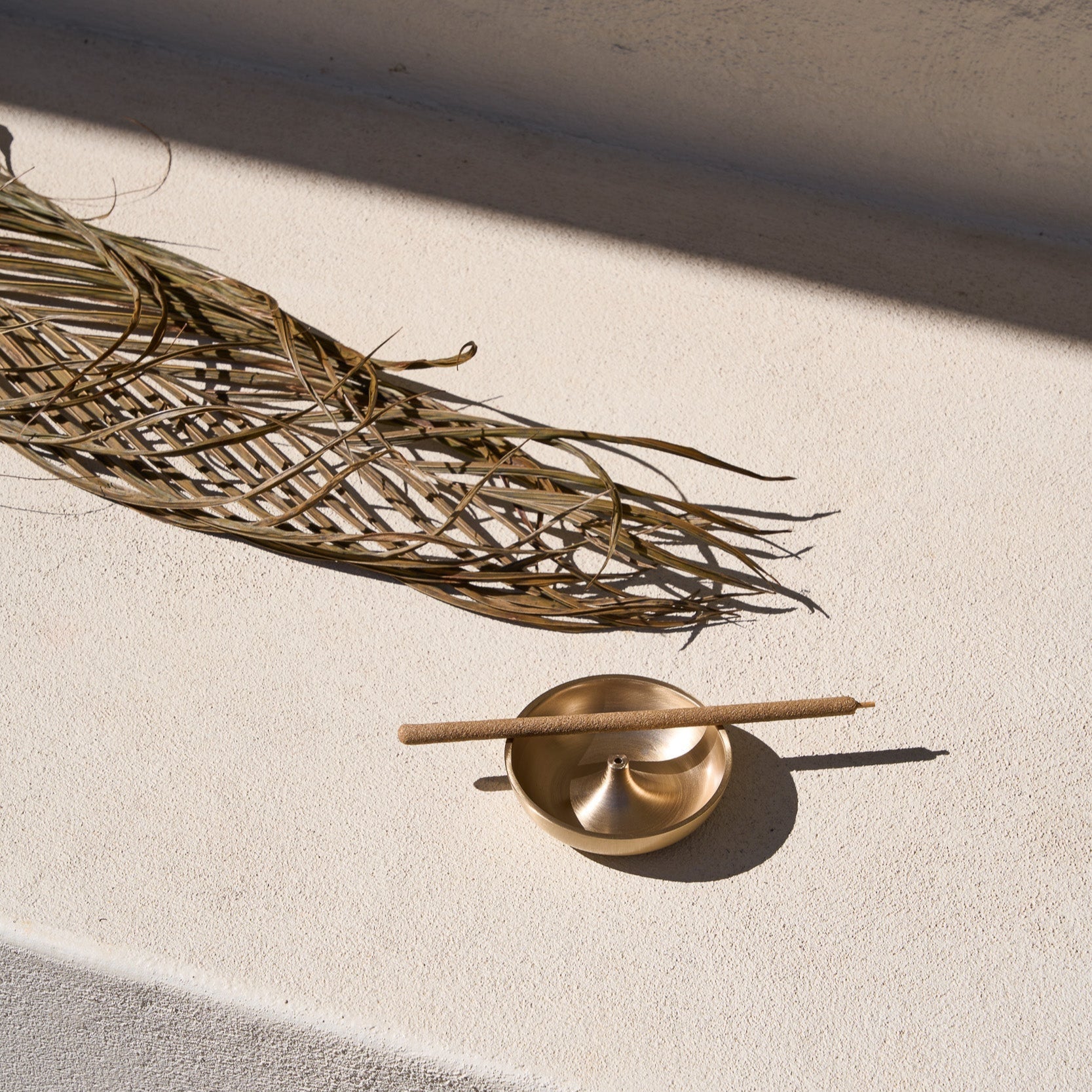 Templ Palo Santo incense stick in a brass incense holder, styled for meditation.