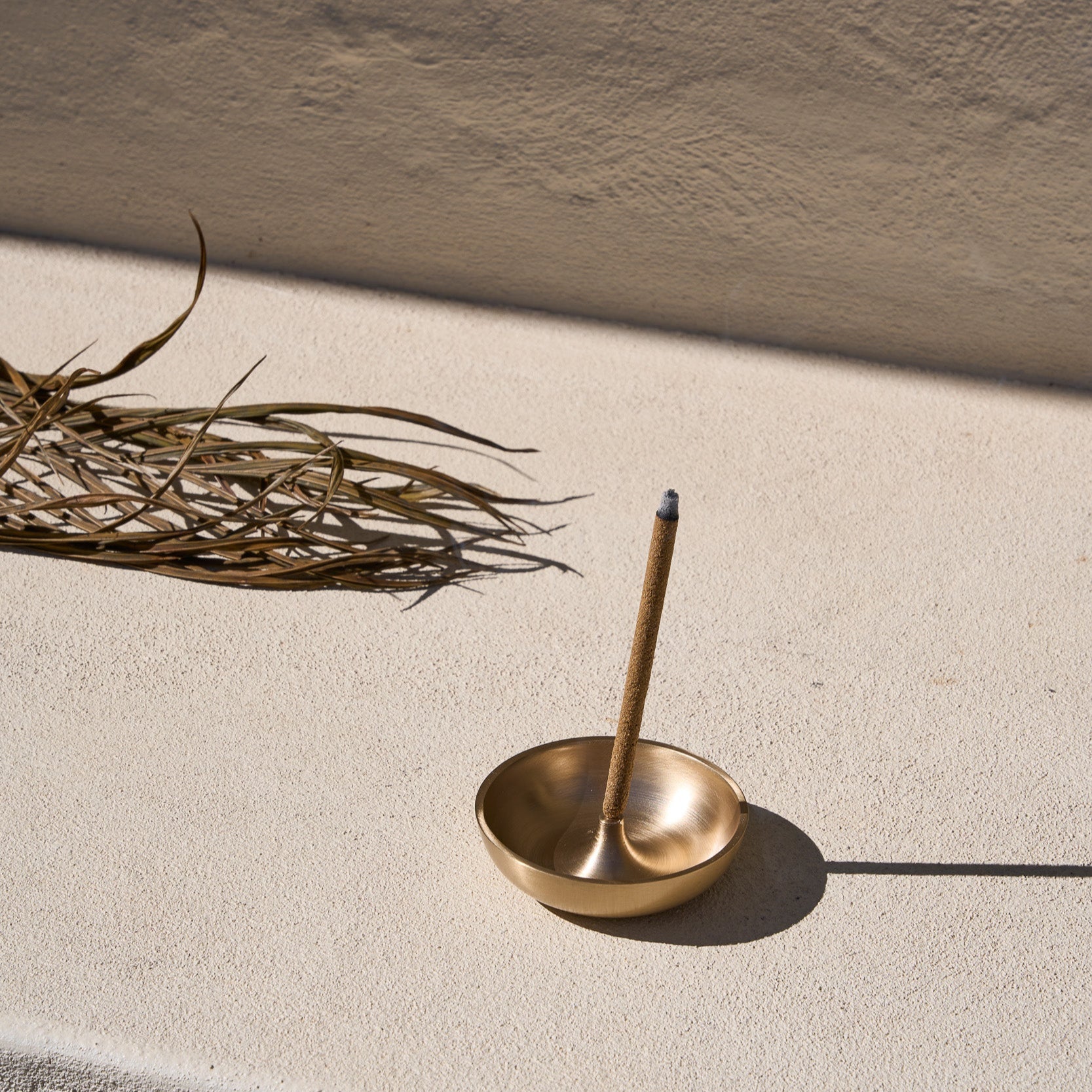 Templ Palo Santo incense stick burning in a brass incense holder, styled for meditation.