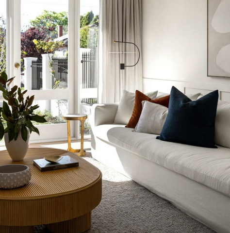 Modern living room with our Ayla Cream sofa, wooden coffee table, and decorative pillows.