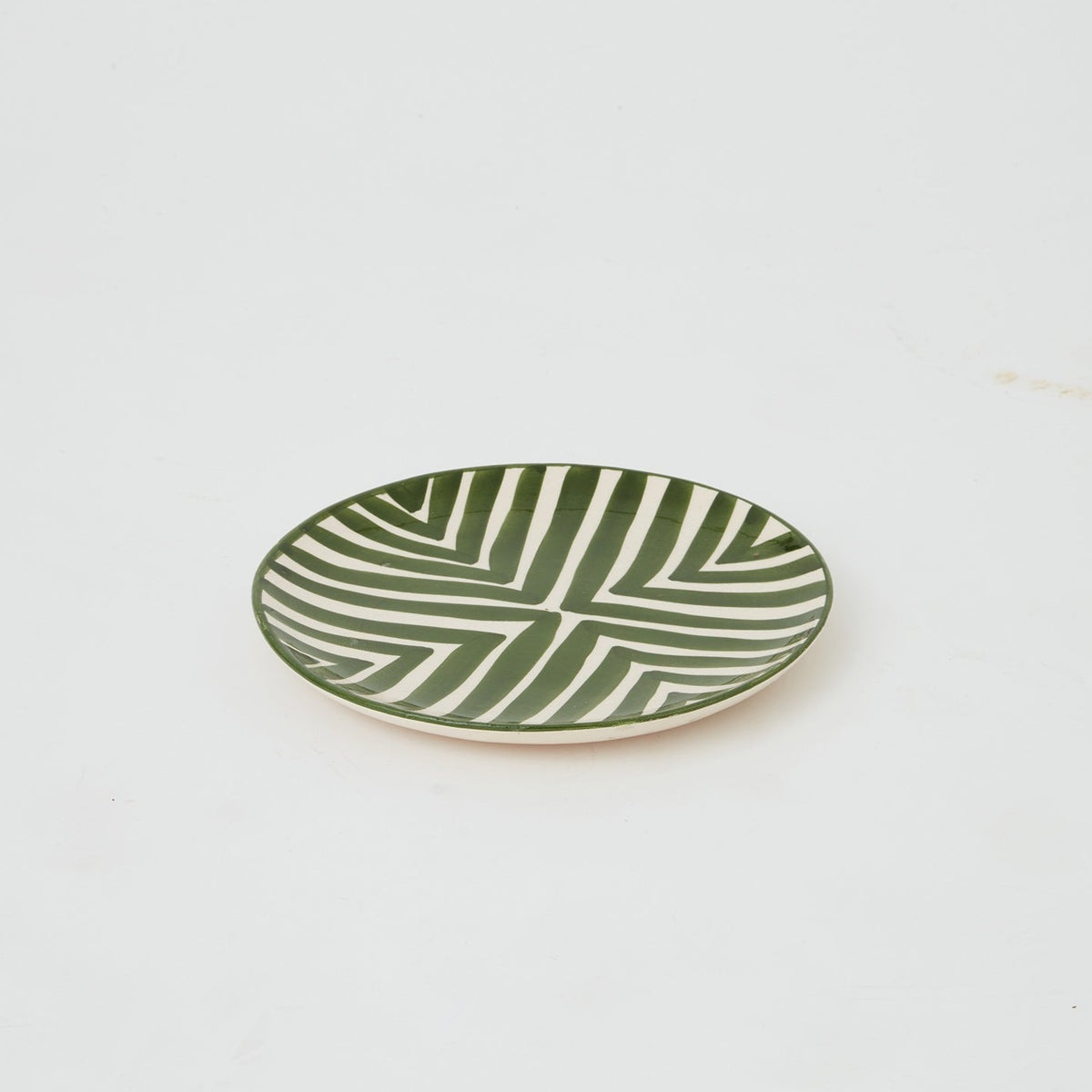 Close-up of handmade Moroccan ceramic plate in green with bold geometric design, ideal for stylish dining and table display.
