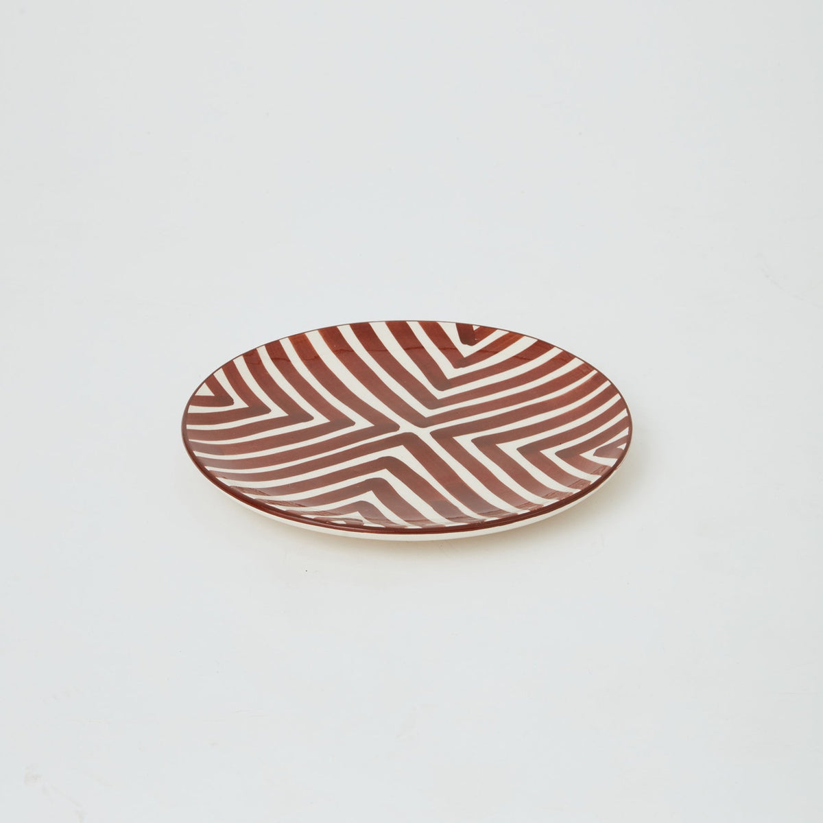 Close-up of handmade Moroccan ceramic plate in brown with bold geometric design, ideal for stylish dining and table display.