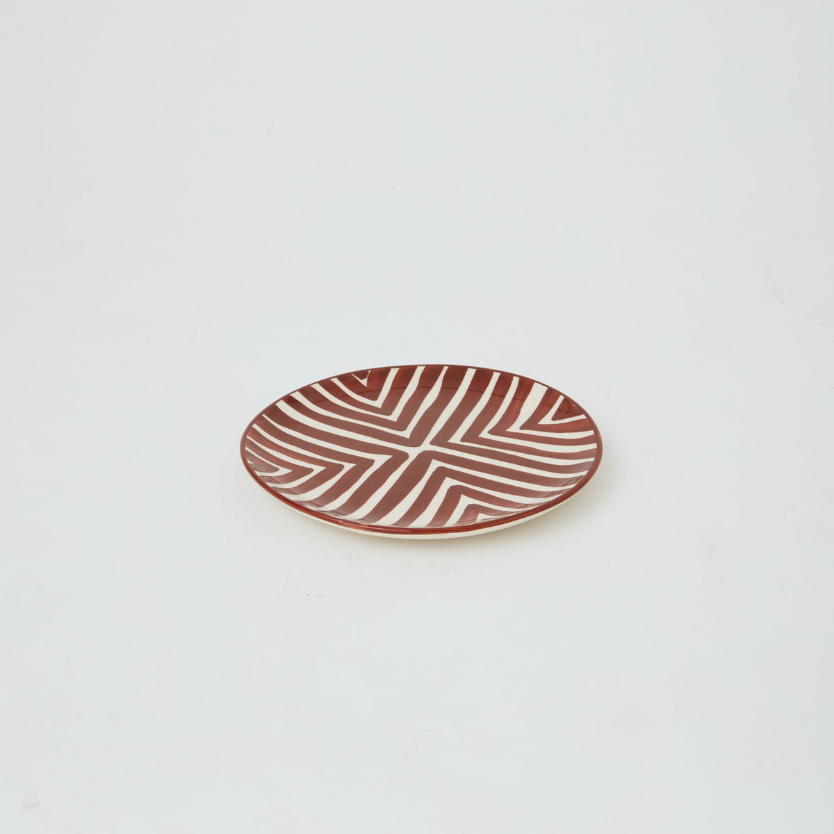 Close-up of handmade Moroccan ceramic plate in brown with bold geometric design, ideal for stylish dining and table display.