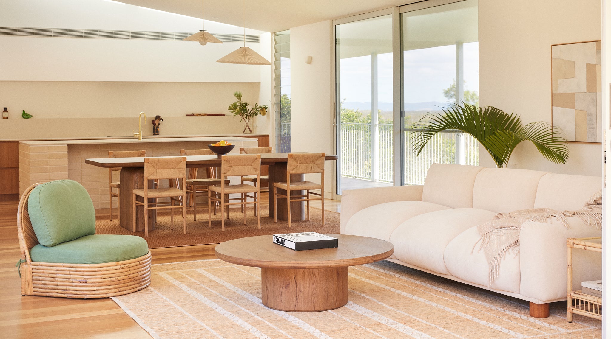 Sumi 3 Seater Sofa in Oatmeal Beige fabric styled with the Pablo Rattan Armchair in Fern fabric and the Alta Round Coffee Table in Aged Brown Oak.