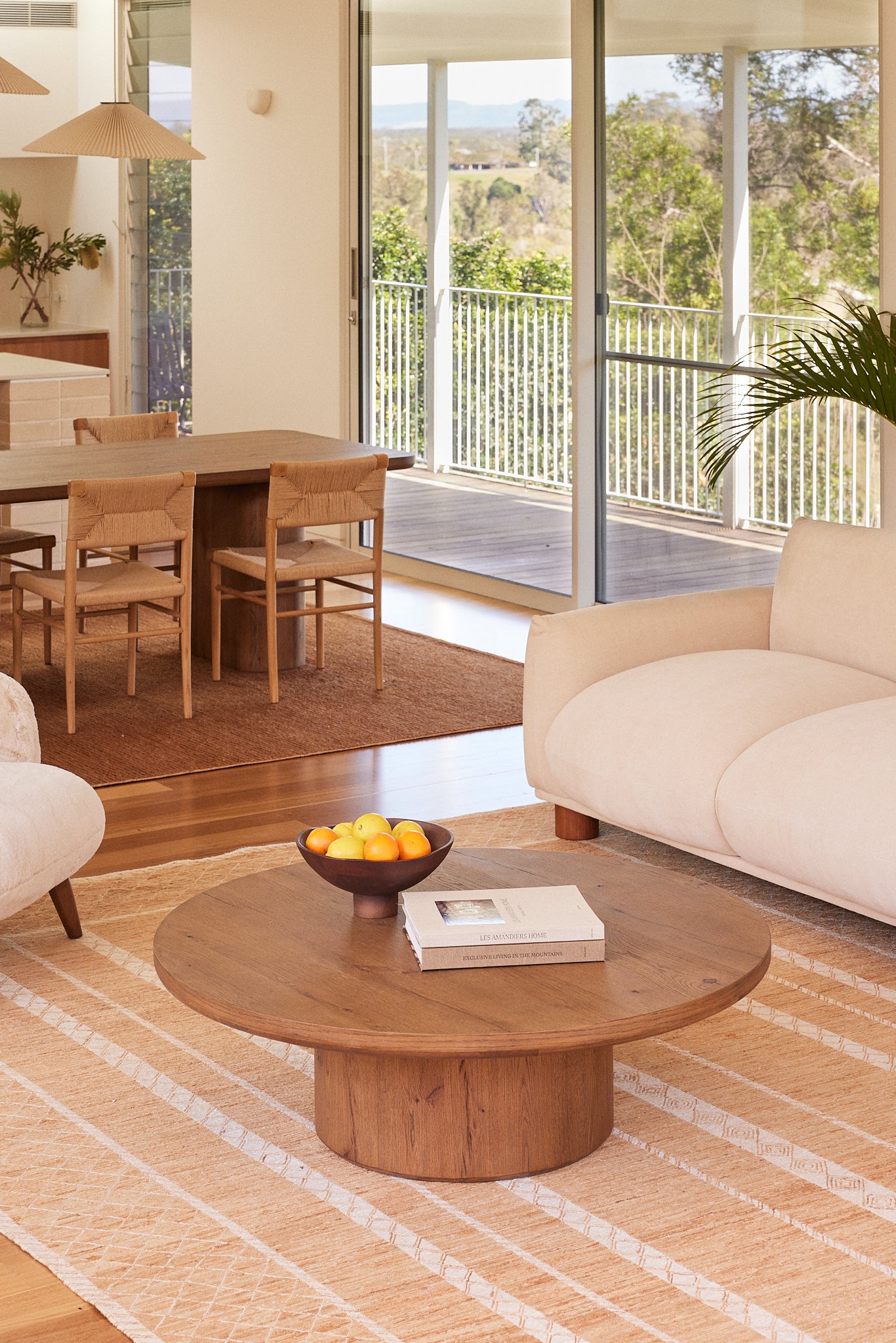 Alta round coffee table in aged brown oak on a textured rug in a modern living room