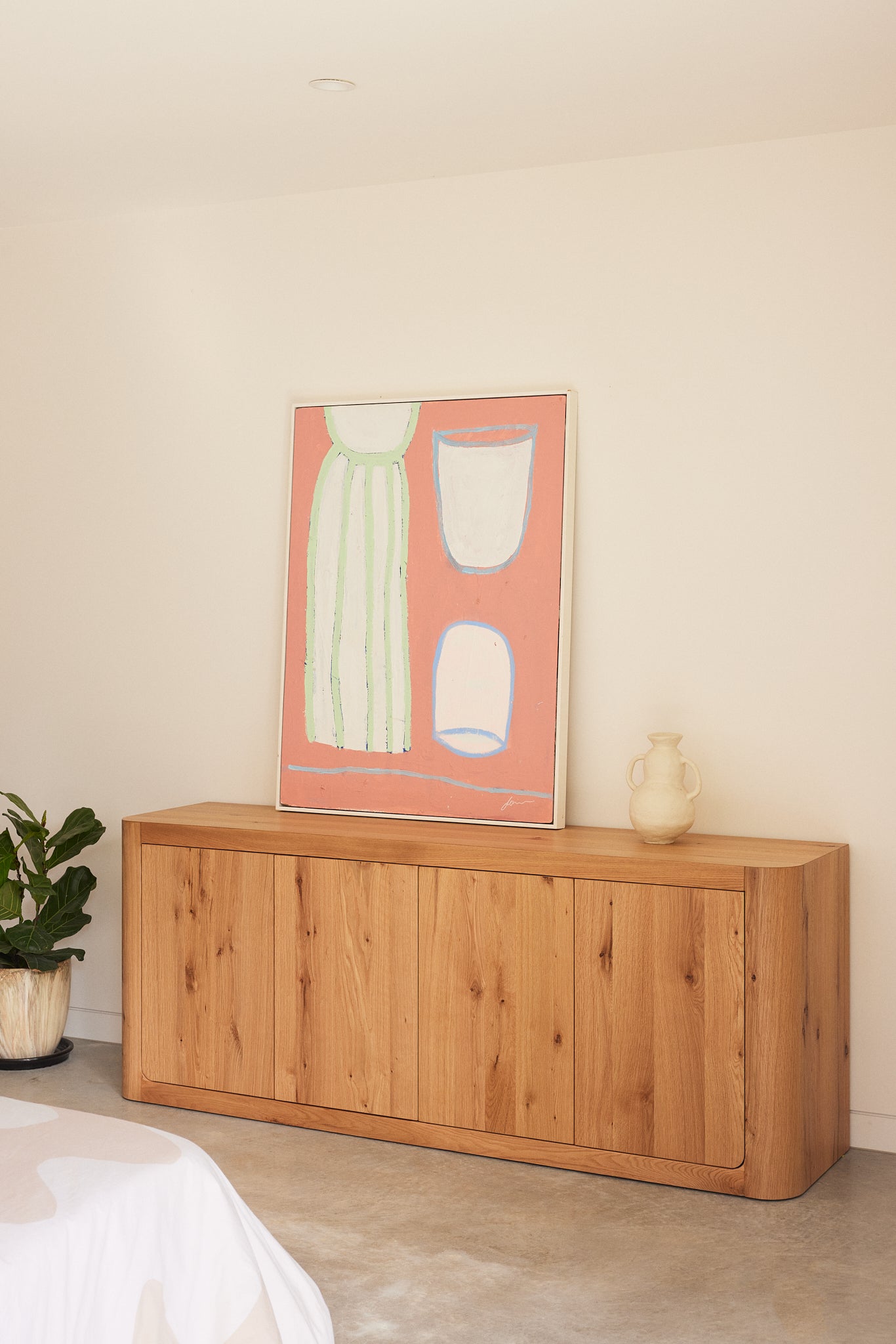 Oslo 4-Door Buffet in Natural Oak styled with contemporary artwork and decorative objects in a modern living space.