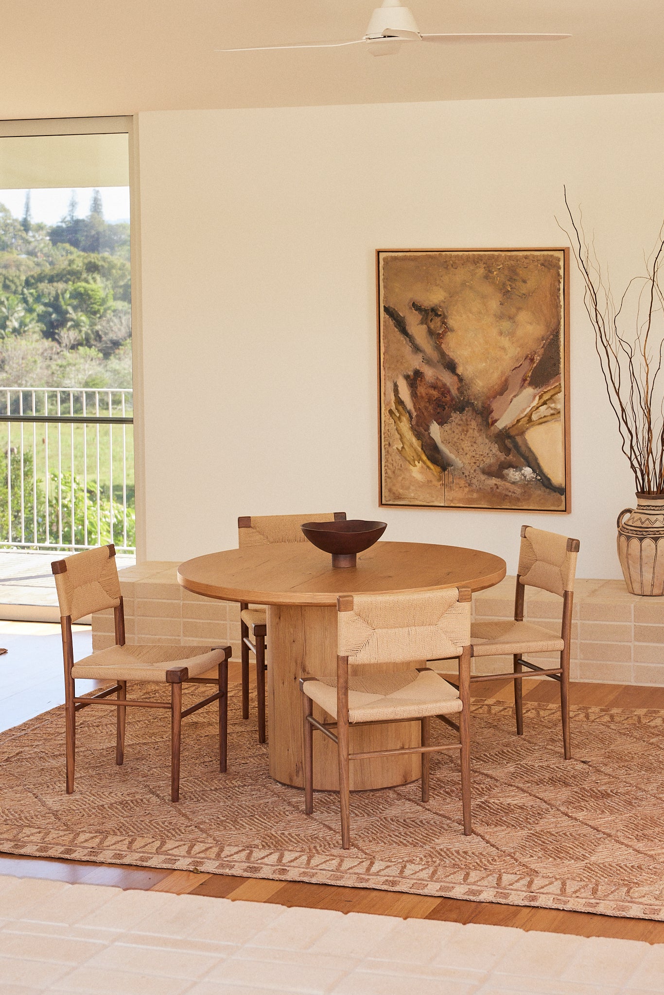 Large Tuareg textured rug in natural jute styled with the Alta round dining table in natural Oak and Azul dining chairs in Oak with woven rope in a contemporary Australian dining room.