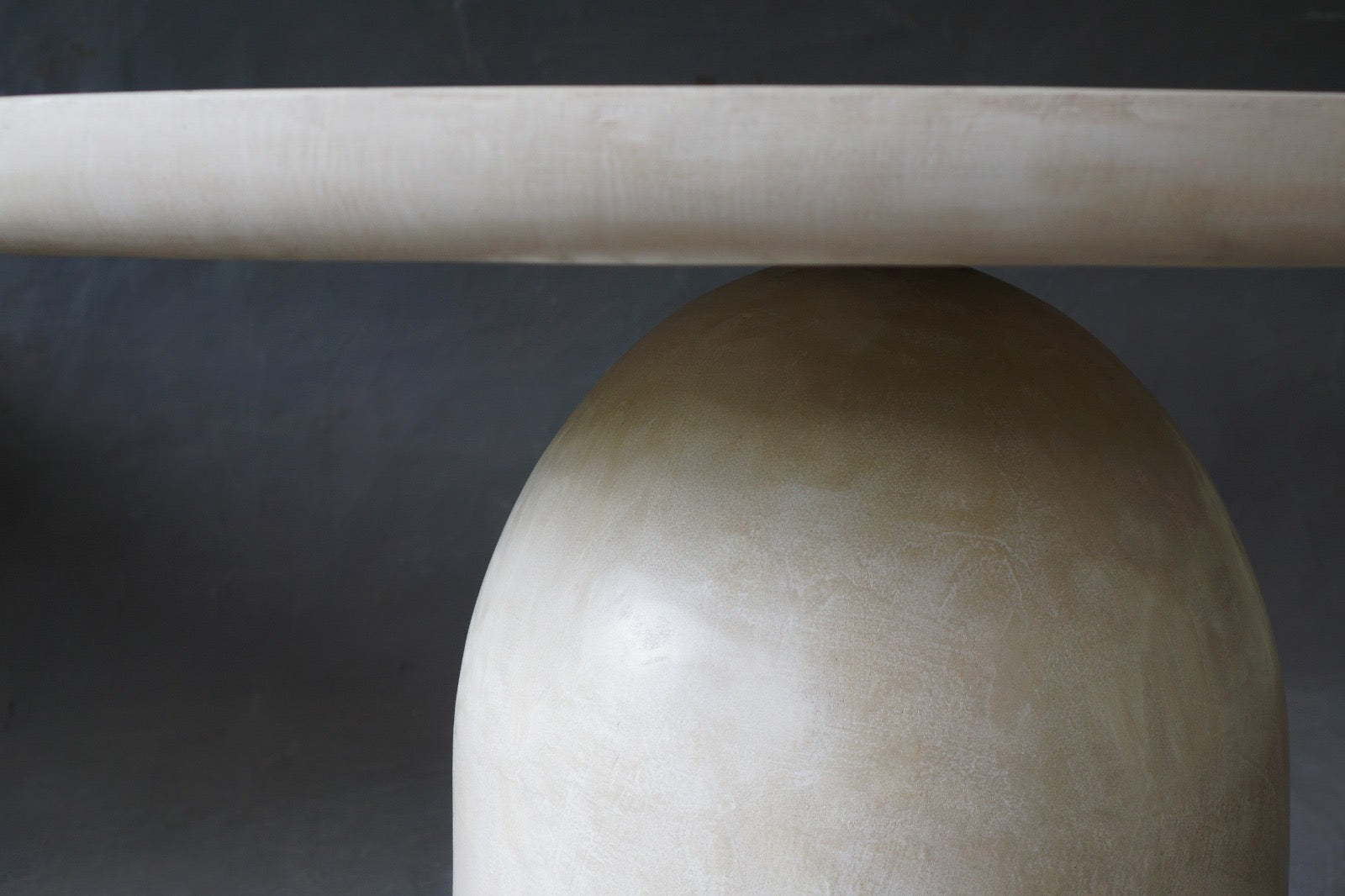 Closed-up of the Nexus Round Dining Table in Oyster highlighting smooth micro cement finish.