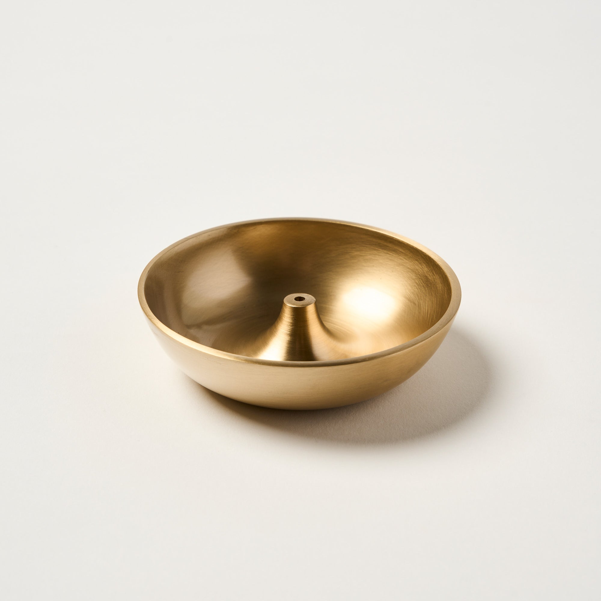 Close-up of Templ brass incense holder with smooth rounded finish, artisanal detail.