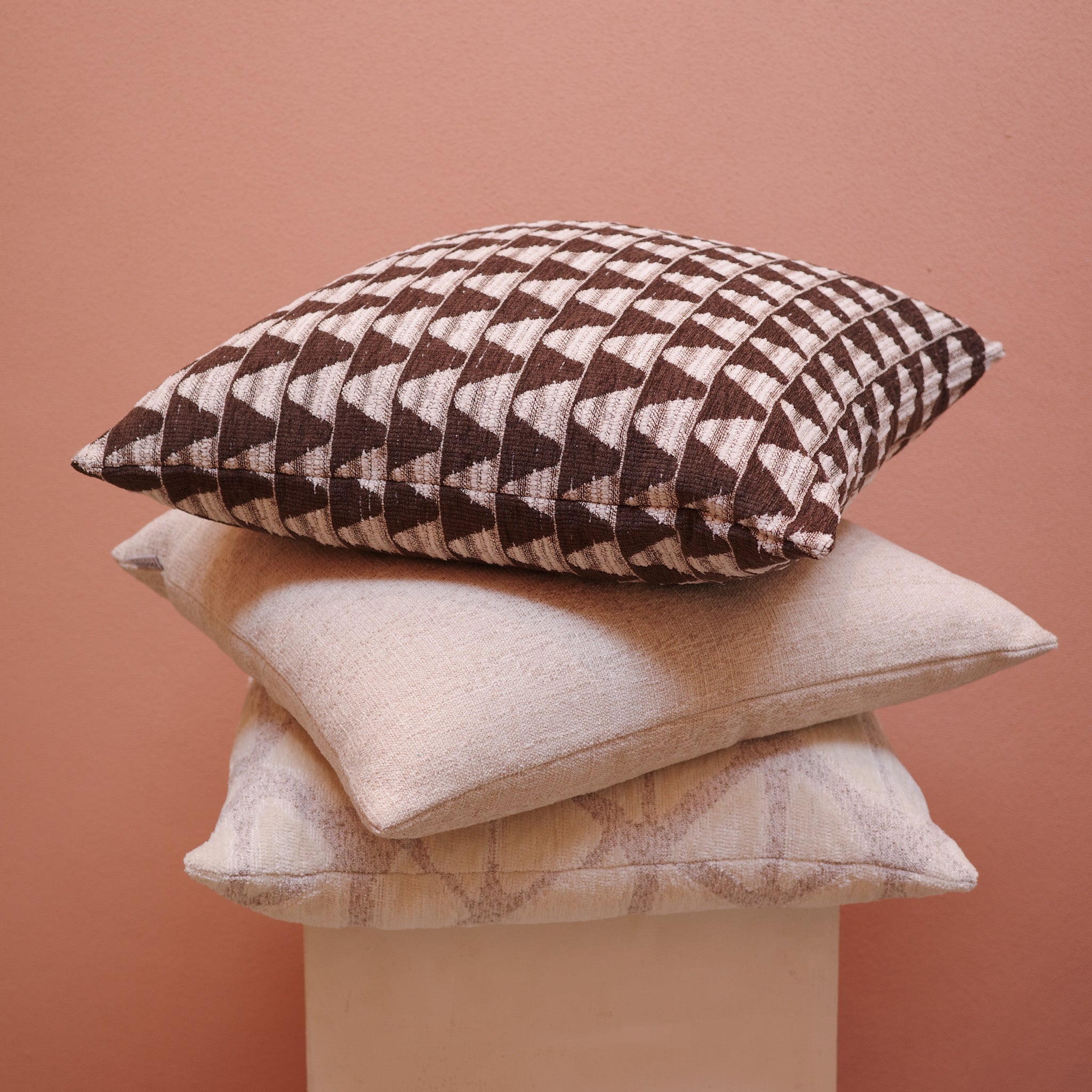 Stack of Bodhi Living cushions in neutral and geometric fabrics