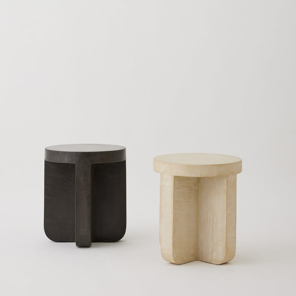 Axel round side tables in micro-cement, shown in Oyster and Pebble finishes with sculptural bases