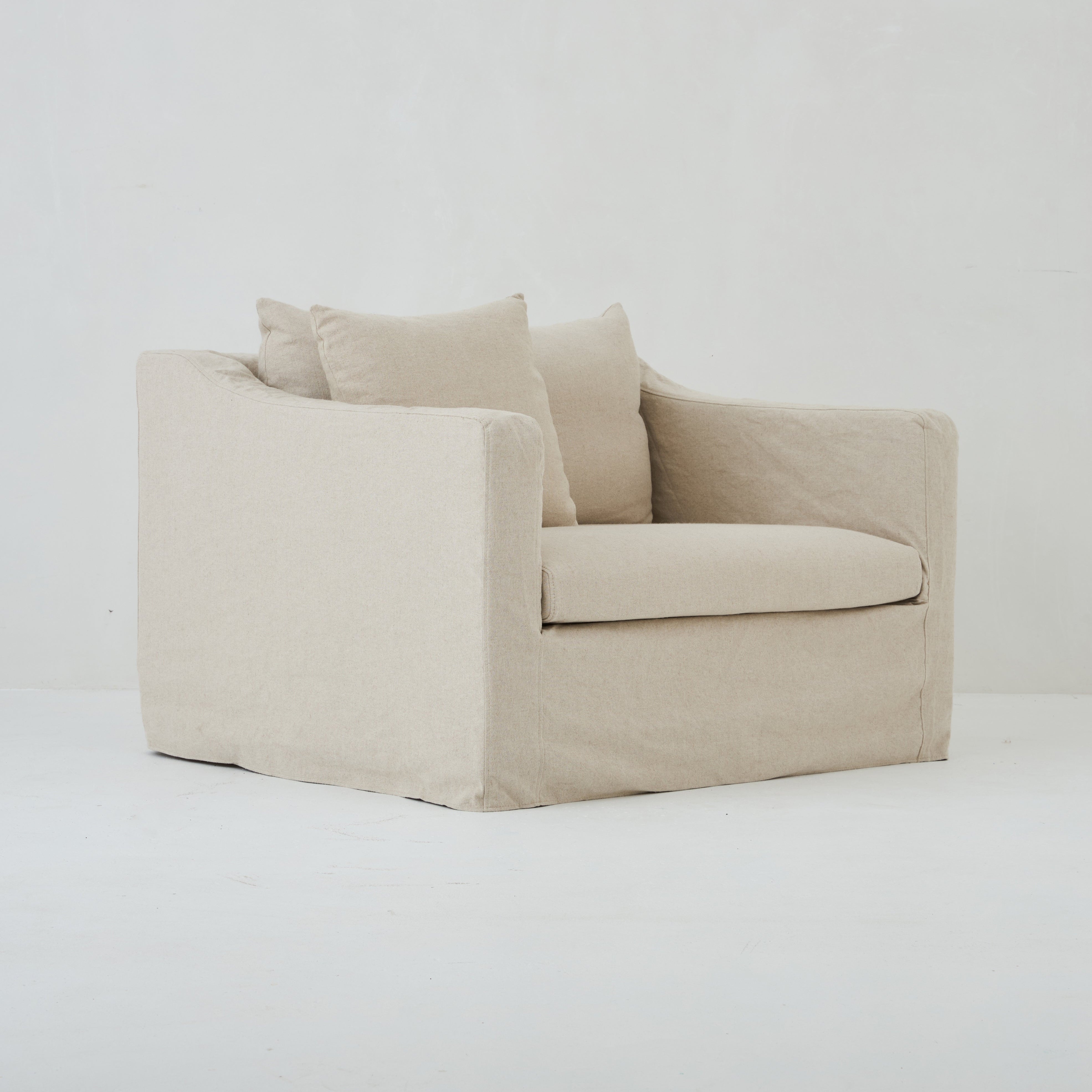 Side profile of the Ayla Armchair with loose linen cover in Natural linen cover
