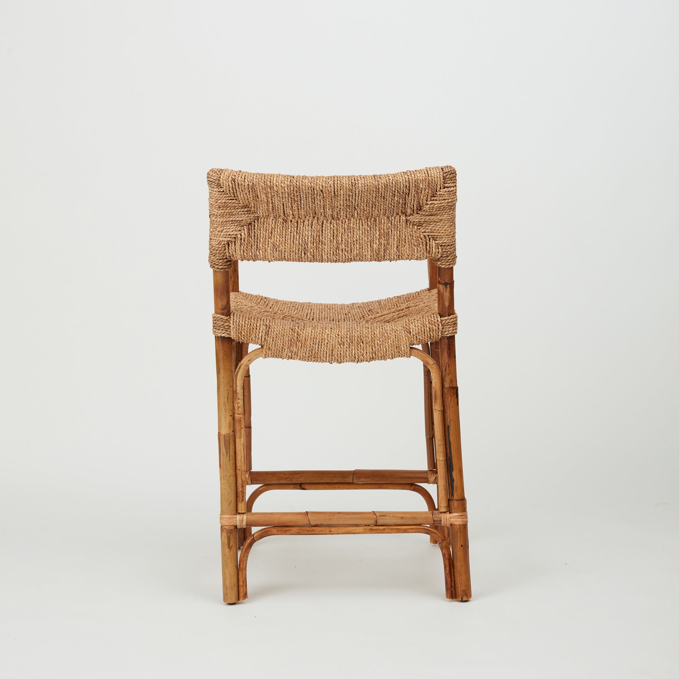 Azul Bar Stool with handwoven rope seat and backrest on natural rattan frame, back view.