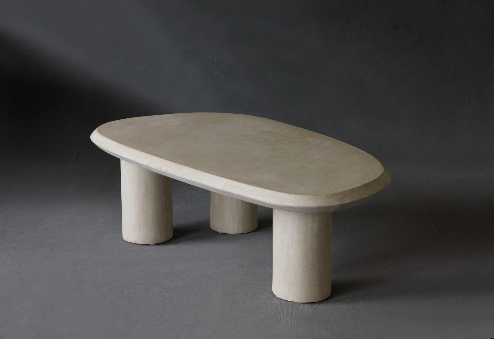 The Bean coffee table features a fluid, organic shape with a Oyster micro-cement finish.