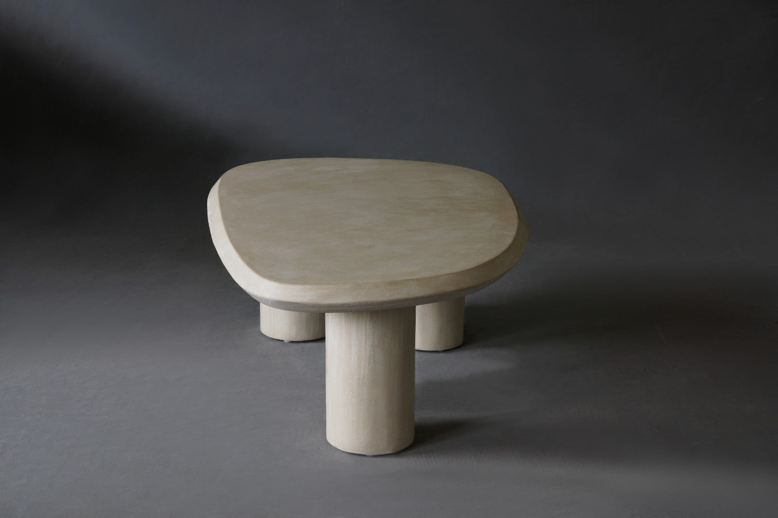 Side view of the Bean coffee table  featuring a fluid, organic shape with an Oyster micro-cement finish.