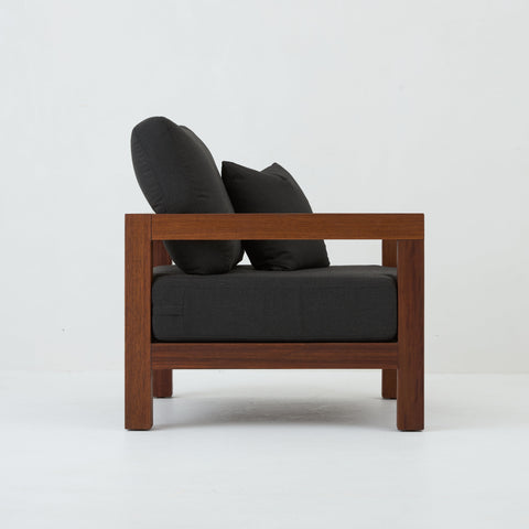 Side view of Cali teak armchair with coal cushions