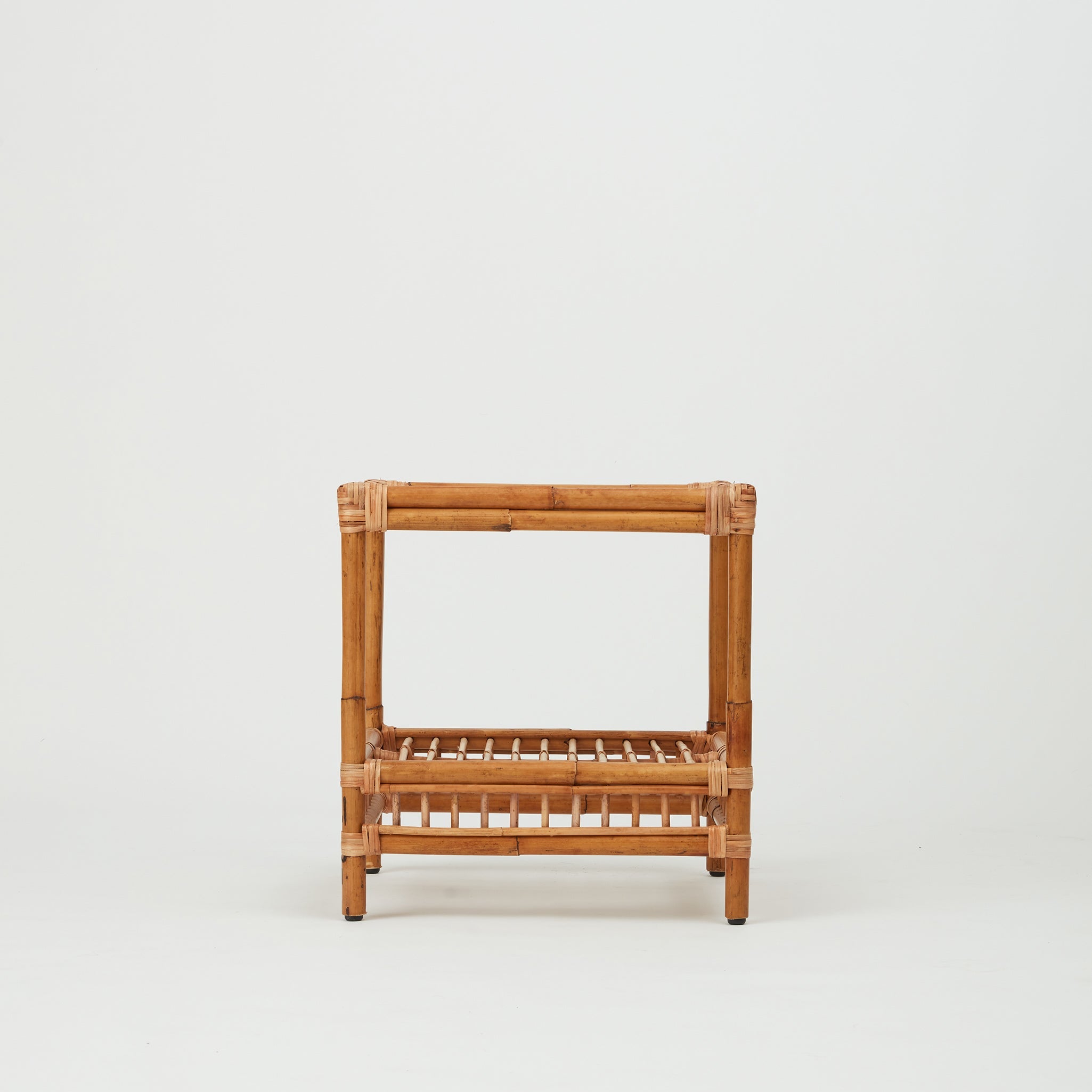 Front view of the Capri rattan side table with glass top and lower rattan shelf.