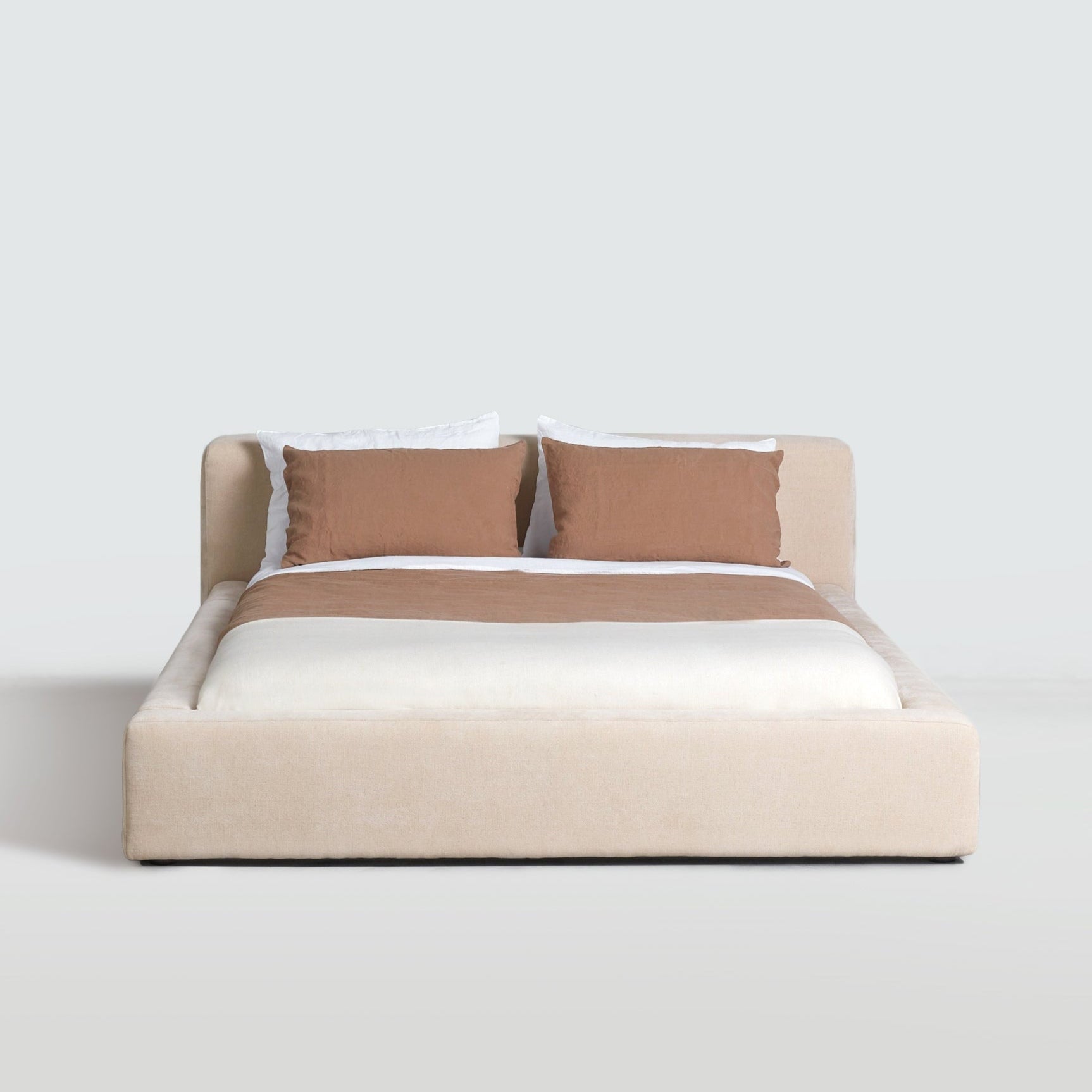 Front view of the Cosmos Bed in Oatmeal with pillows, showing generous headboard and low platform base.