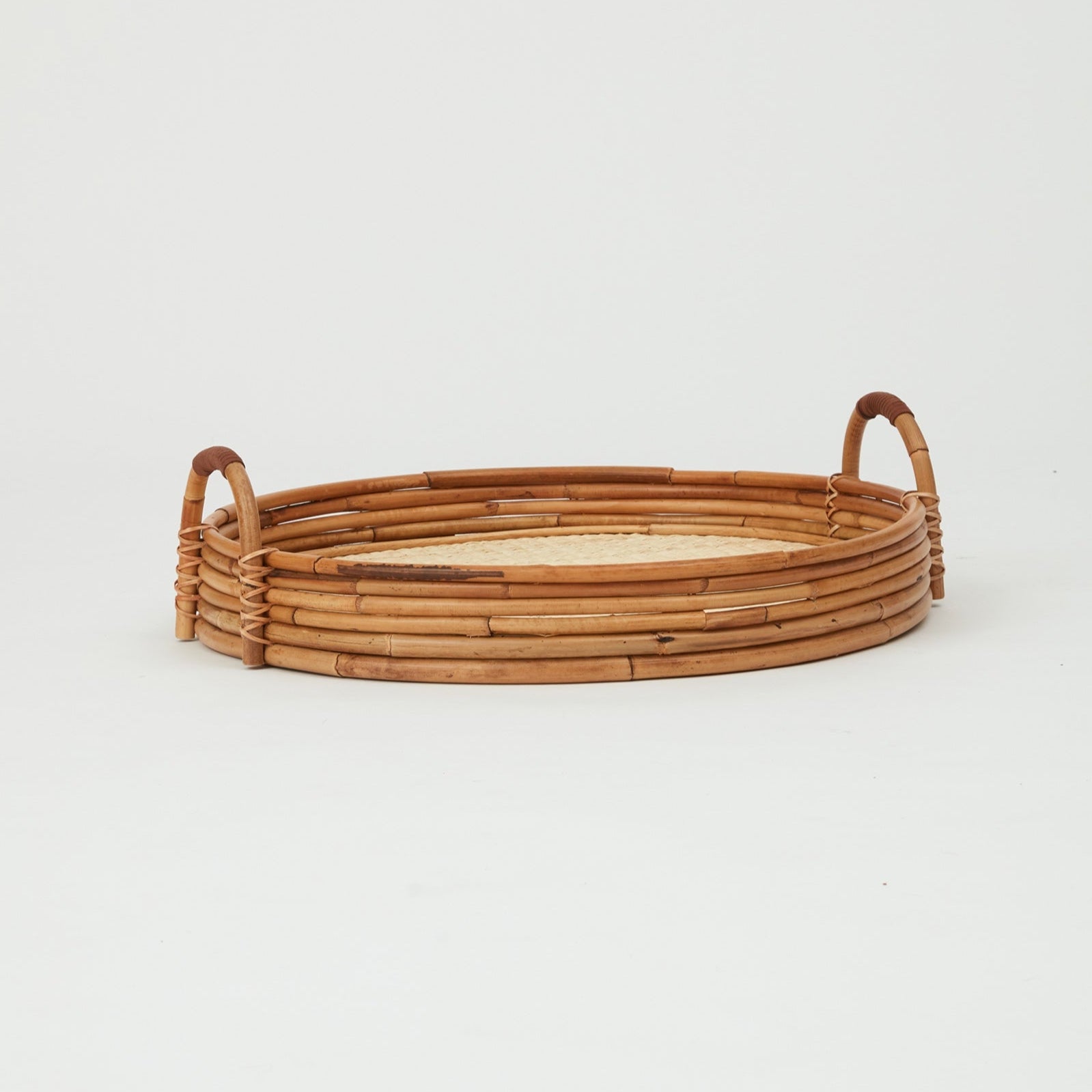 Cuba round serving tray in natural rattan, woven base with raised edges.