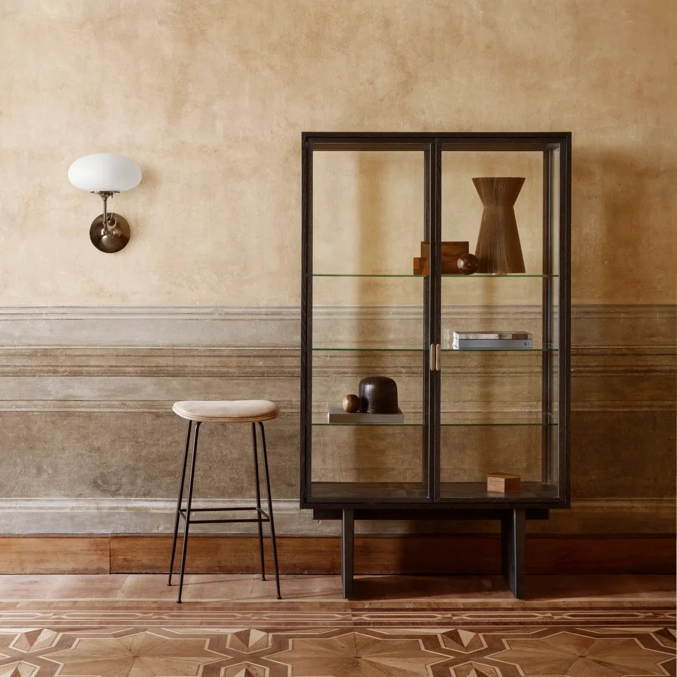 GUBI Private Vitrine in black stained oak styled in a warm-toned room with minimalist decor 