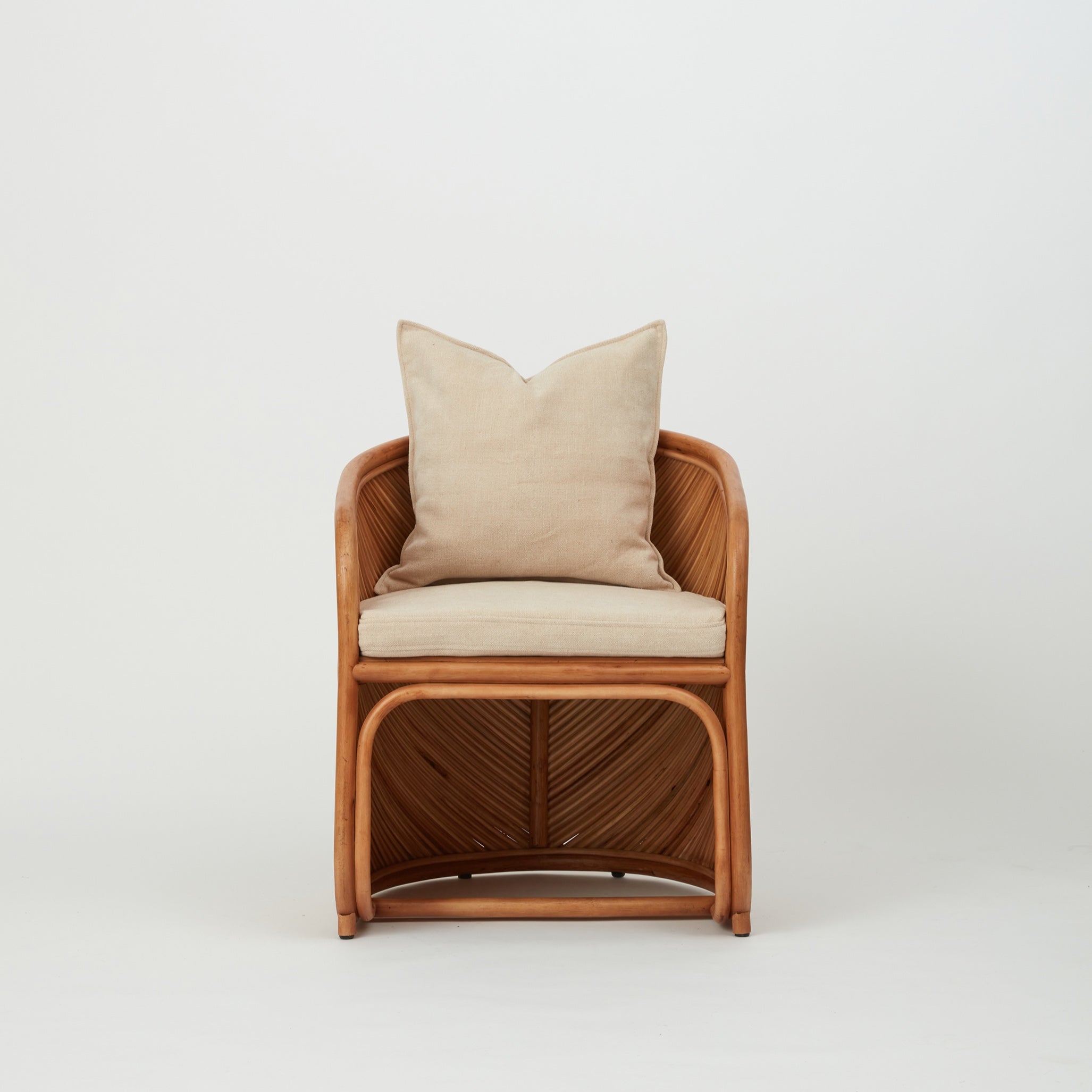 Grace dining chair with sculptural rattan frame and removable upholstered cushions, front angle view.