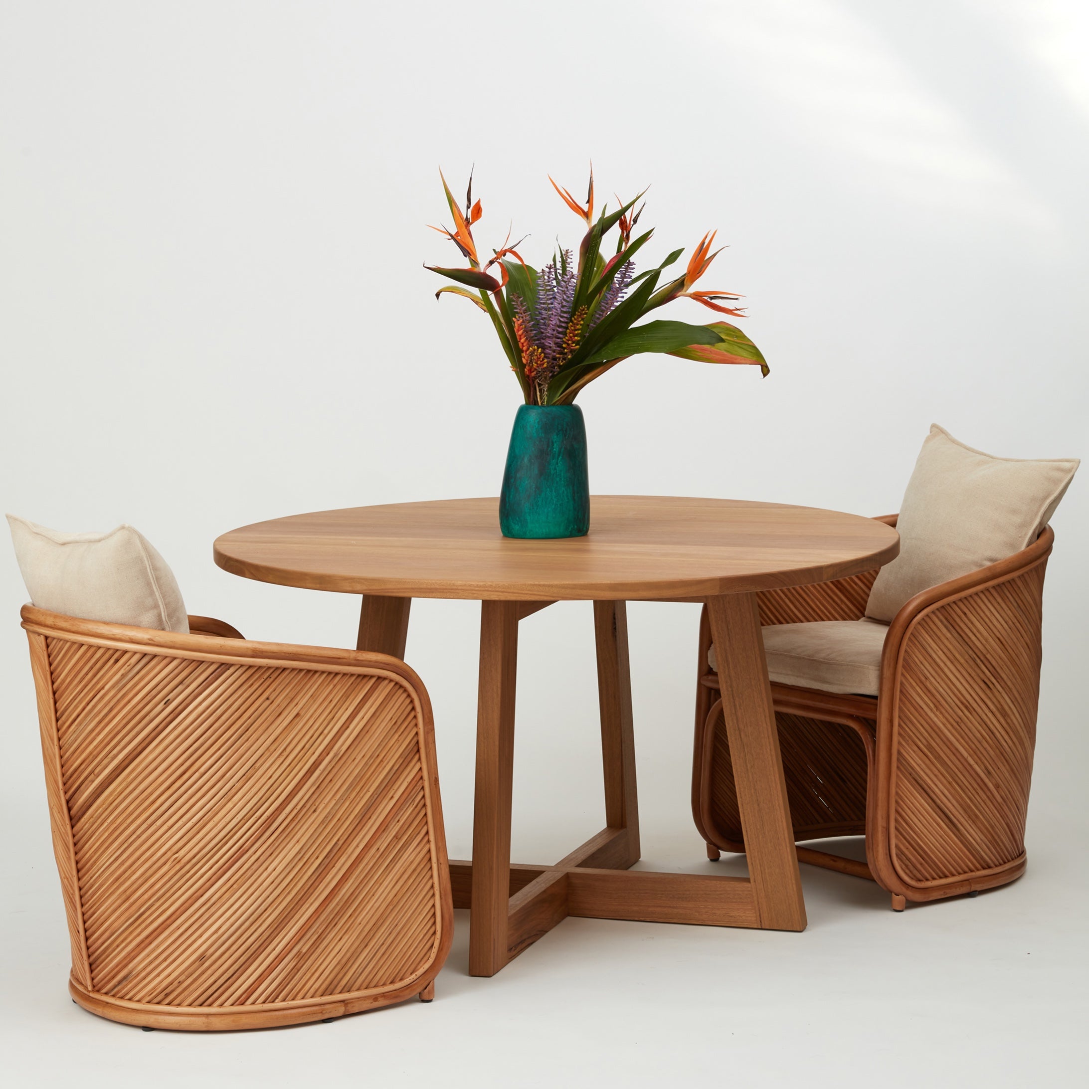 Grace rattan dining chairs styled around a dining table, showcasing curved frame and upholstered cushions.