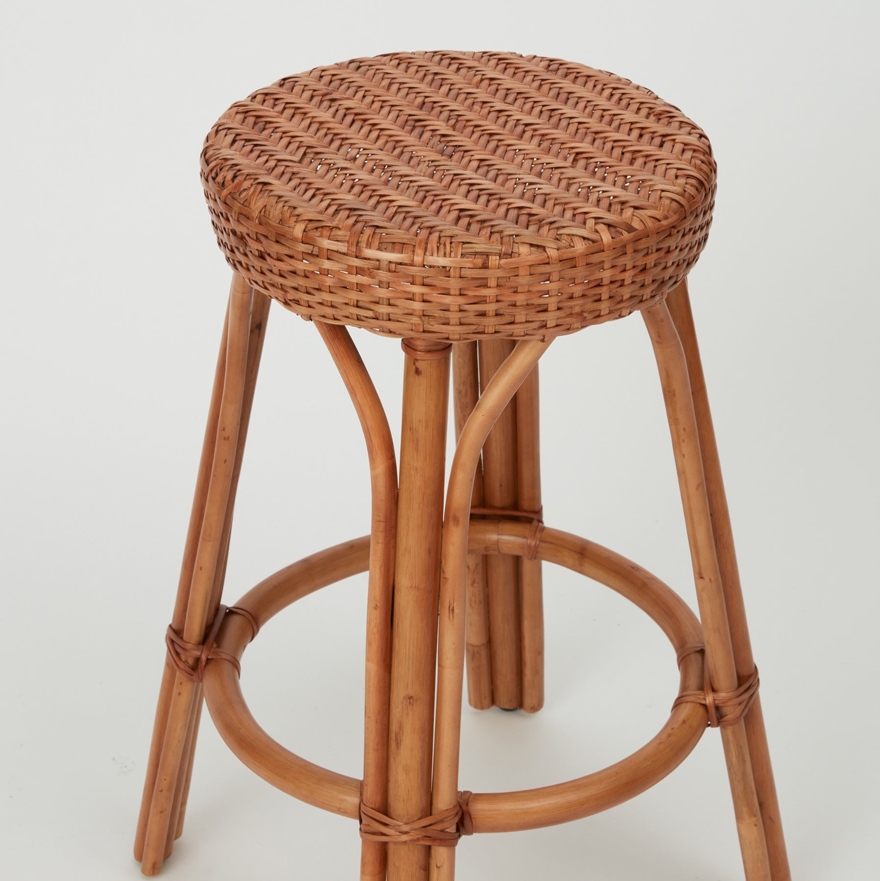 View of the Leila Bar Stool, showing woven seat and arched rattan supports.