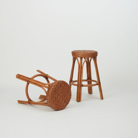 Two Leila Rattan Bar Stools in natural finish, with handwoven seats and round legs.