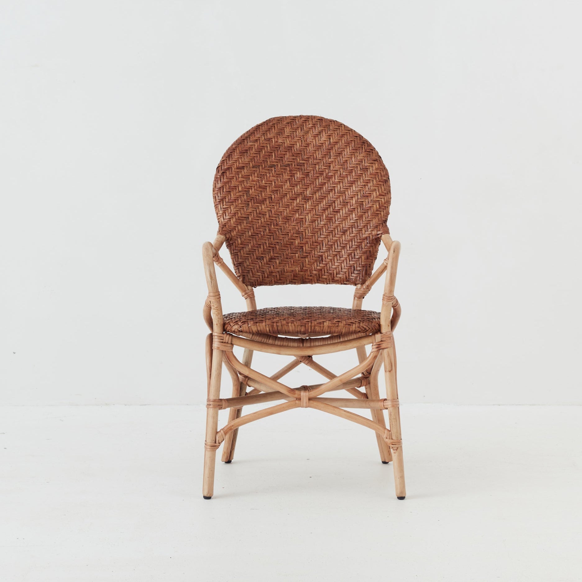 Leila dining chair with handwoven rattan seat and backrest on a natural rattan frame, front view.