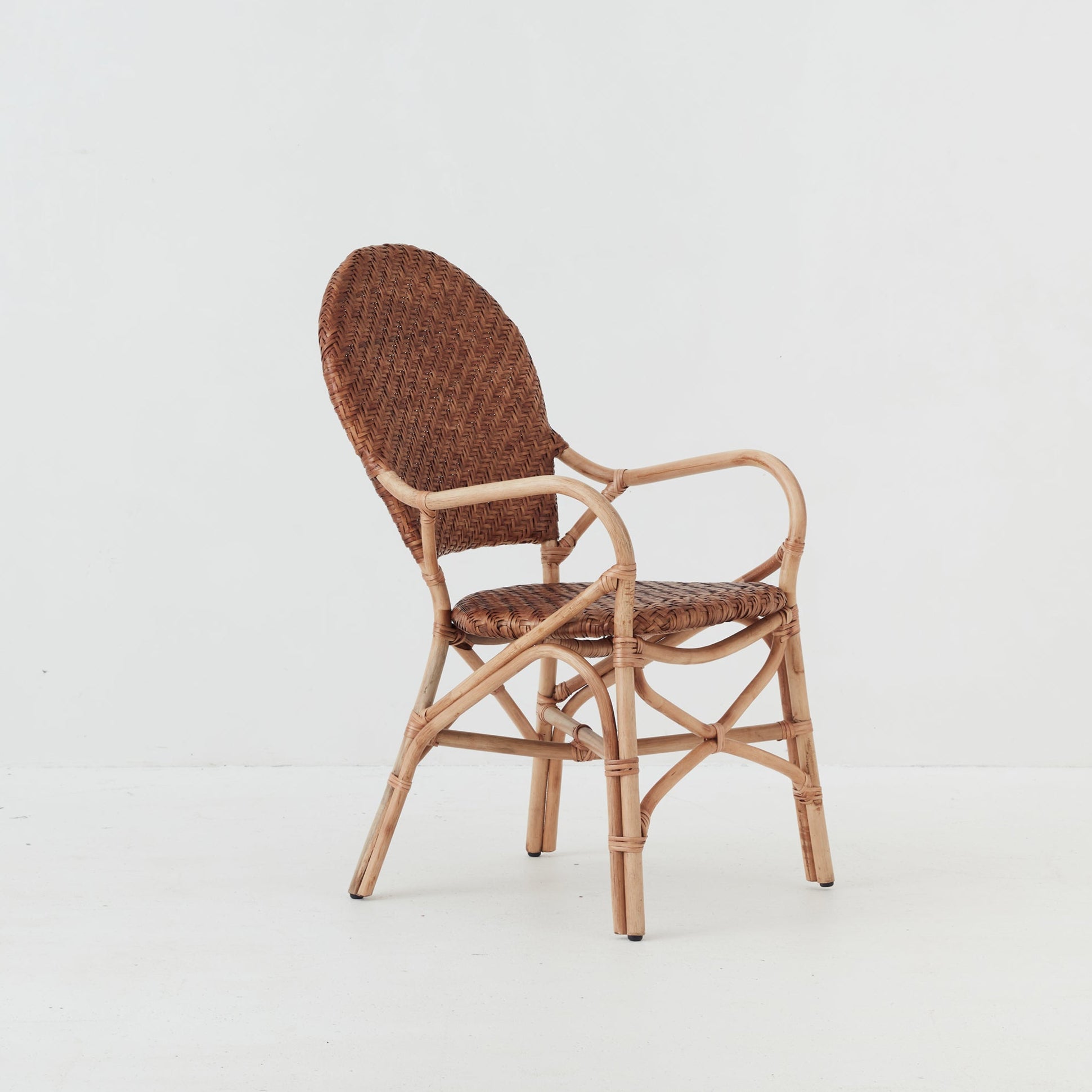 Leila dining chair with handwoven rattan seat and backrest on a natural rattan frame, side view.