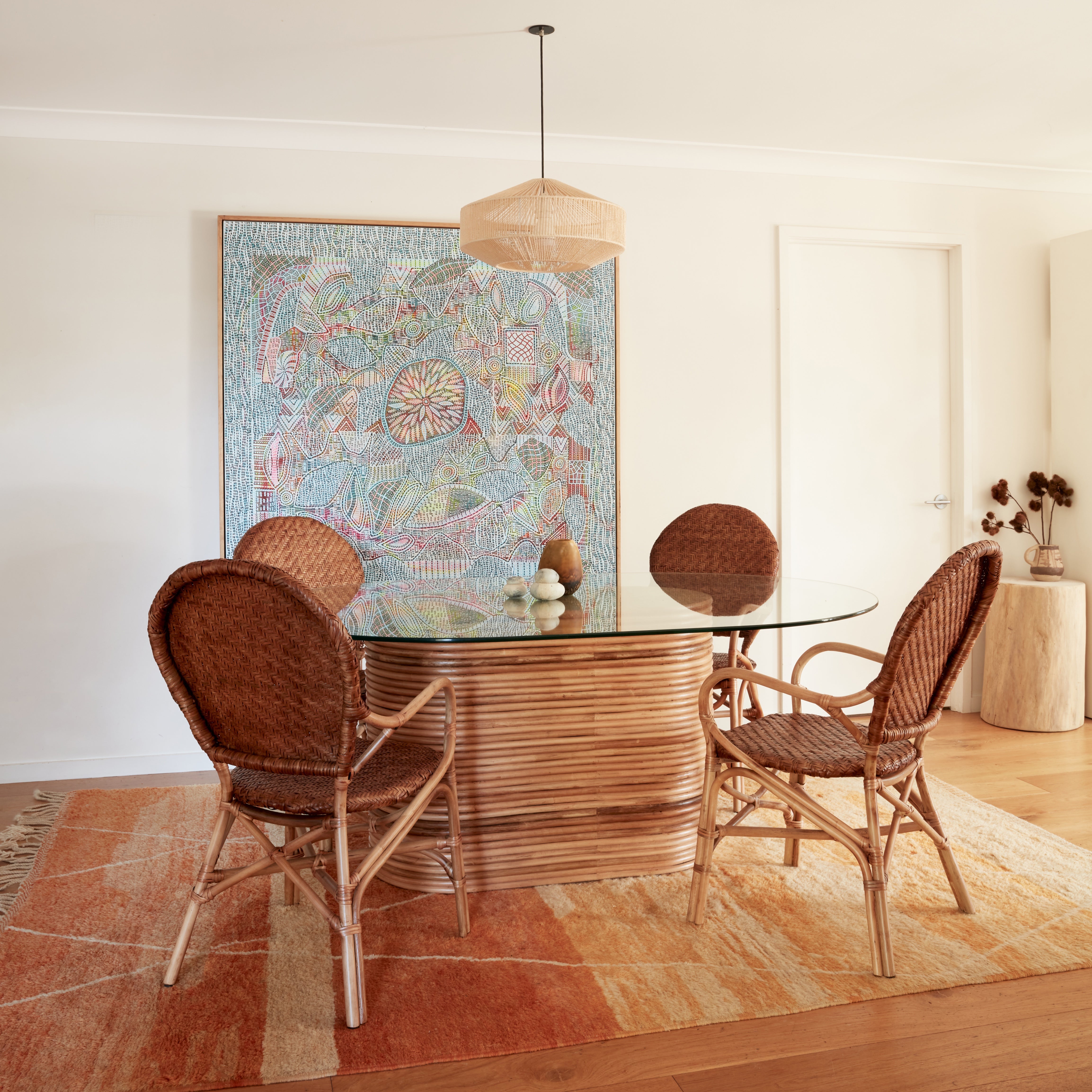 Leila rattan dining chairs styled around the Laguna Dining Table, showing woven backrests and curved arms.