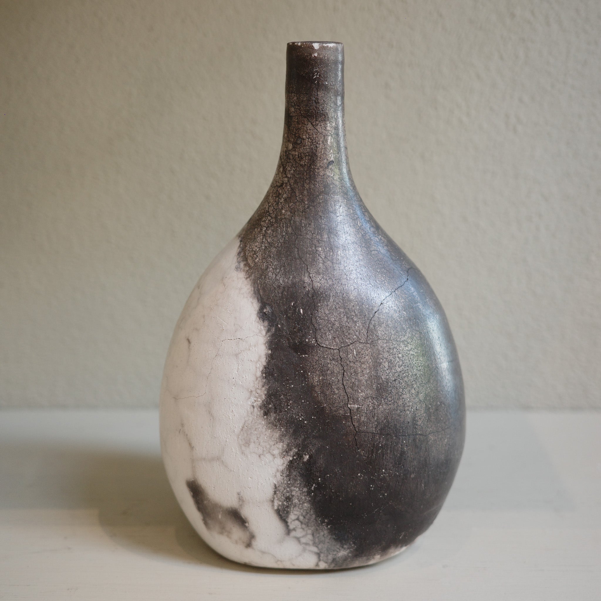 Unique ceramic bottle vase in Naked Raku firing technique, featuring organic smoke patterns.