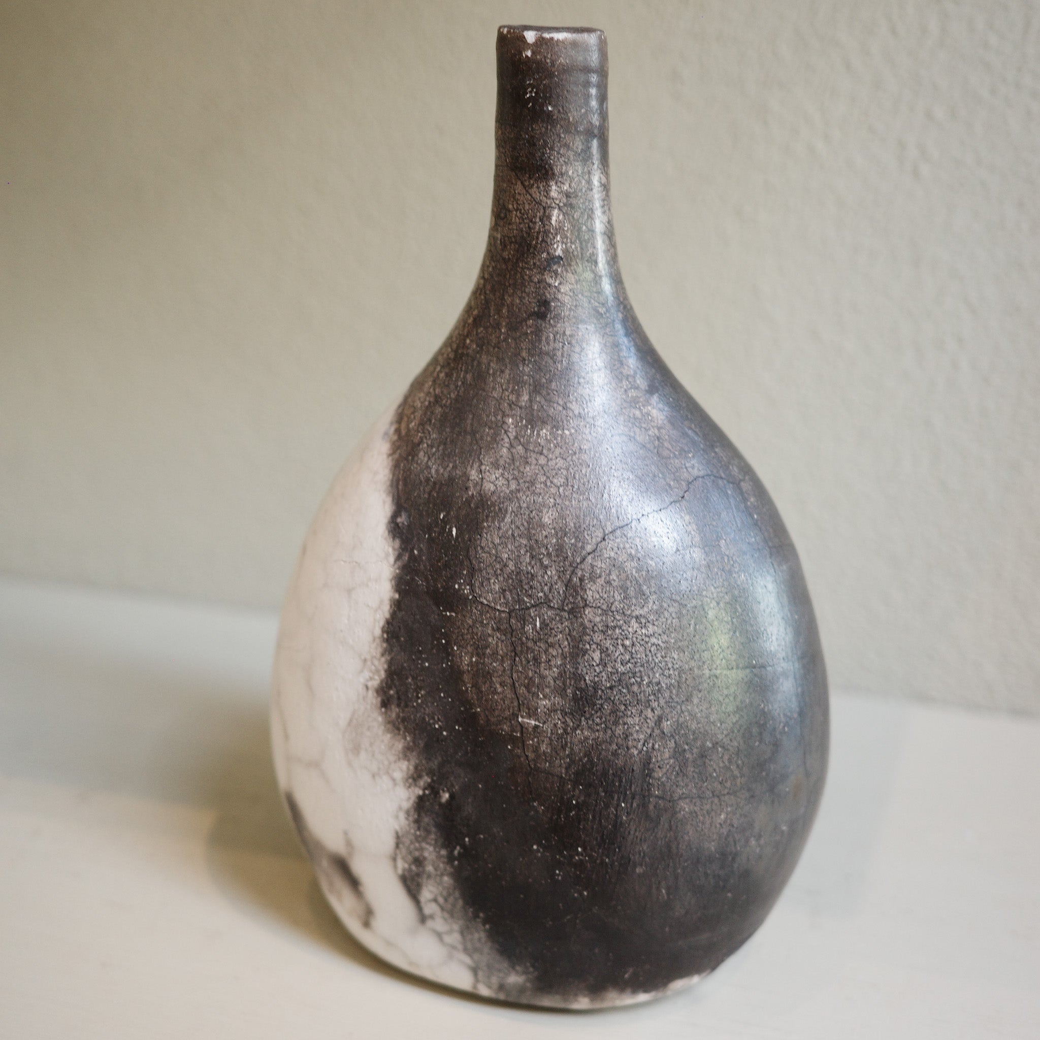 Unique ceramic bottle vase in Naked Raku firing technique, featuring organic smoke patterns.