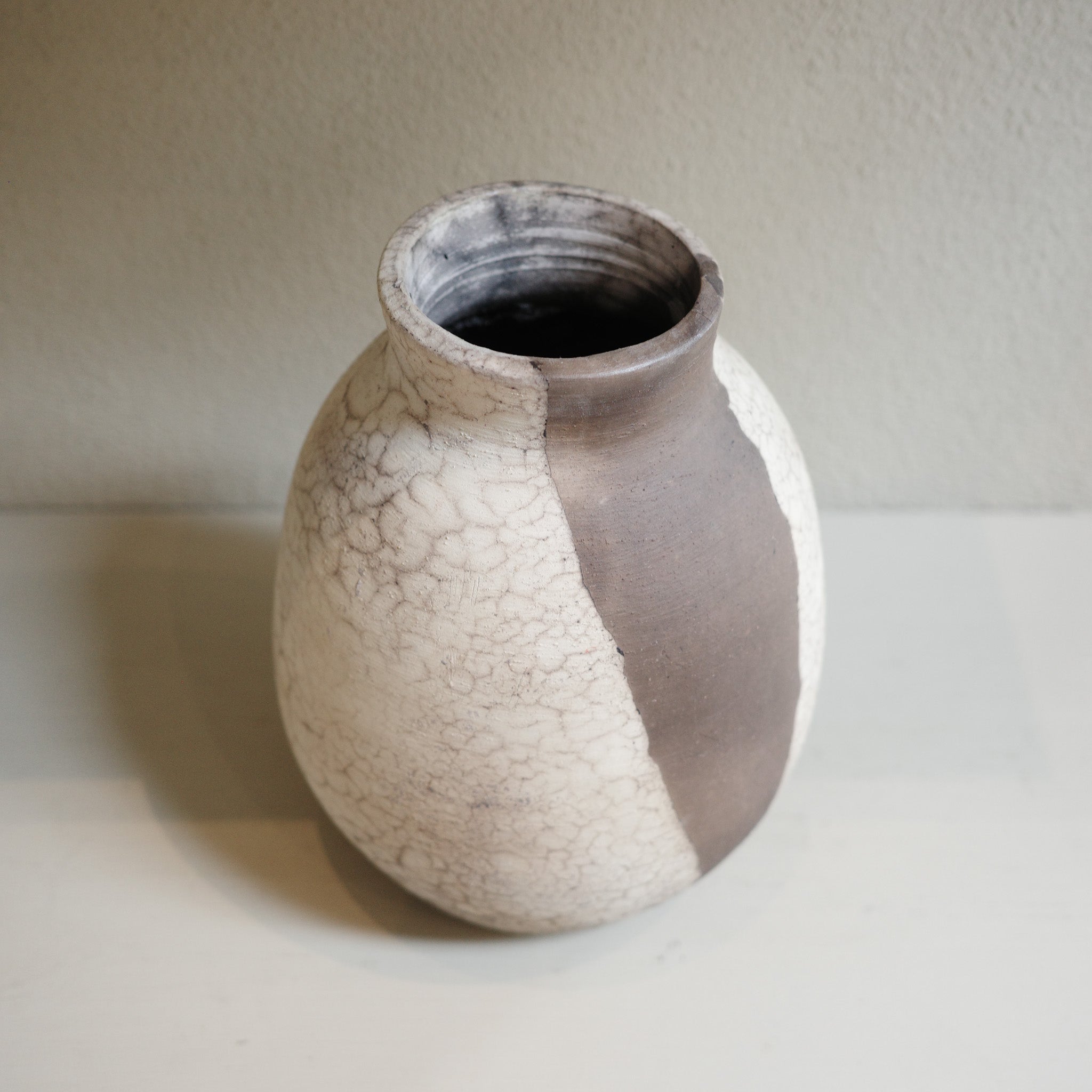 Close-up of naked raku vase showing organic black and white firing patterns