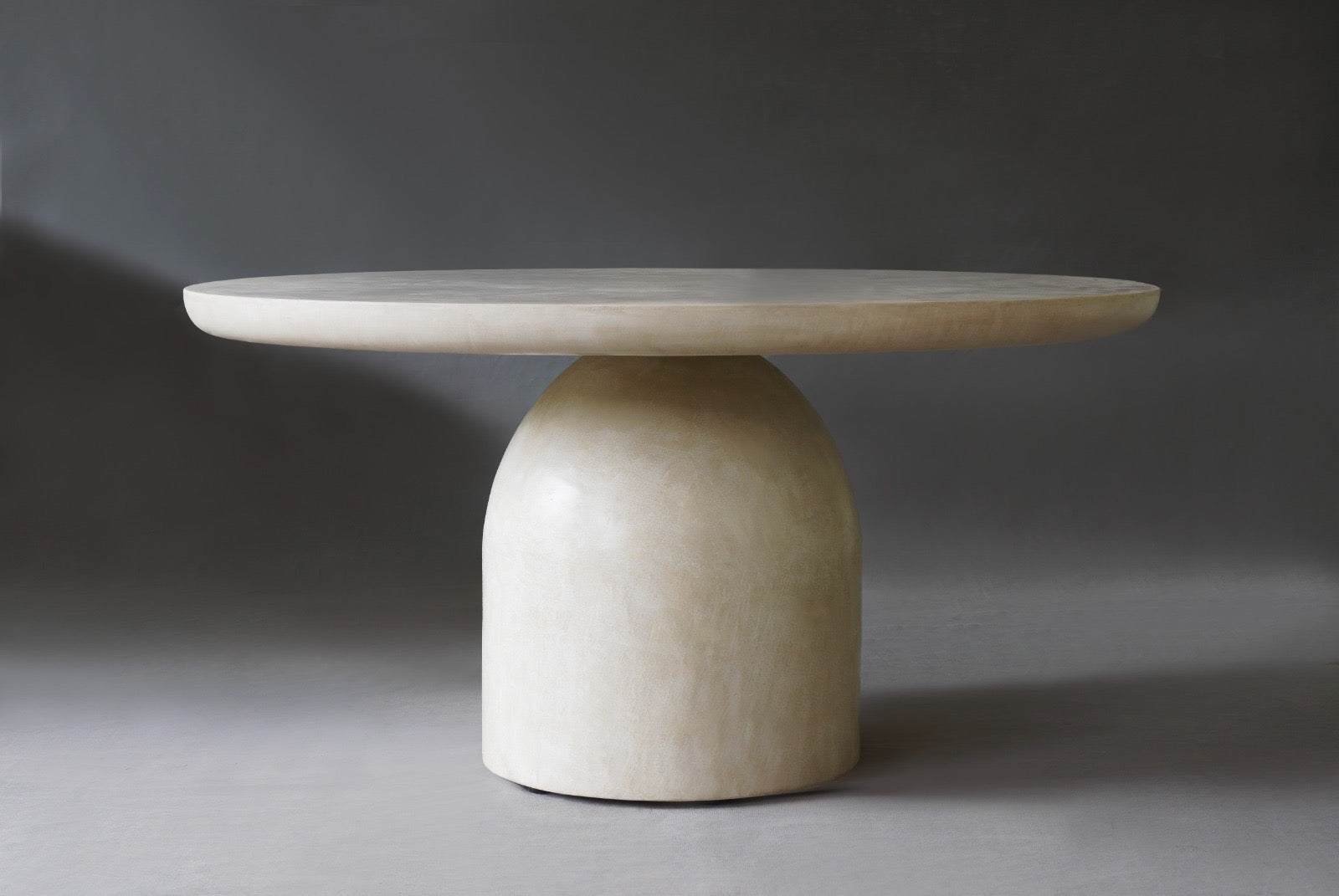 Nexus Round Dining Table in Oyster micro cement finish, showcasing its sleek design and smooth texture.