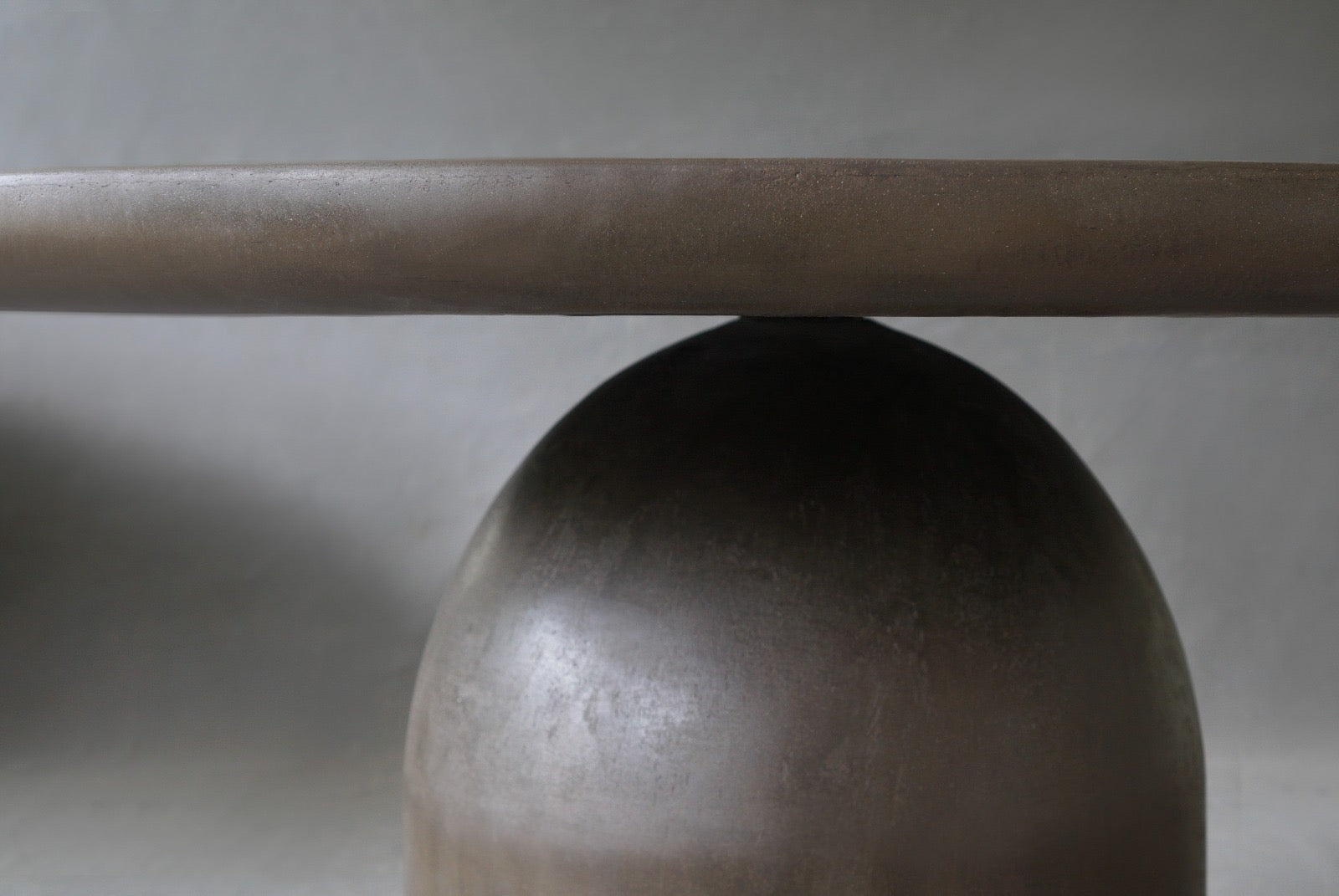 Closed-up of the Nexus Round Dining Table in Pebble highlighting smooth micro cement finish.
