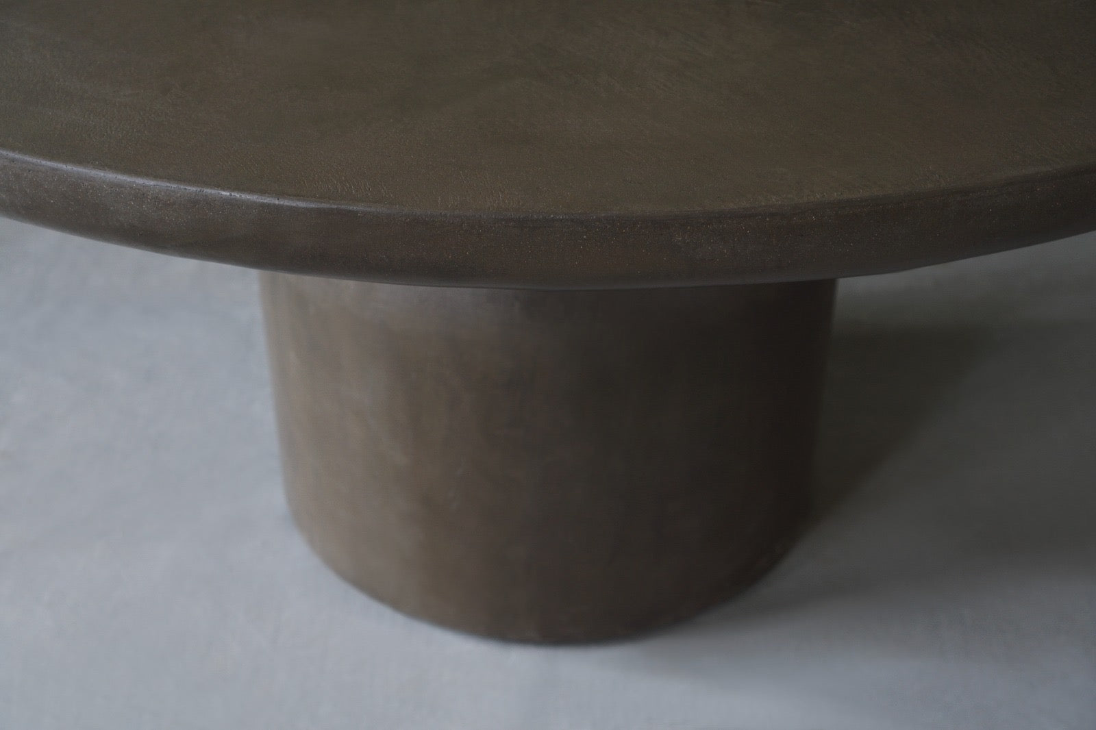 Closed-up side view of the Nexus Round Dining Table in Pebble 