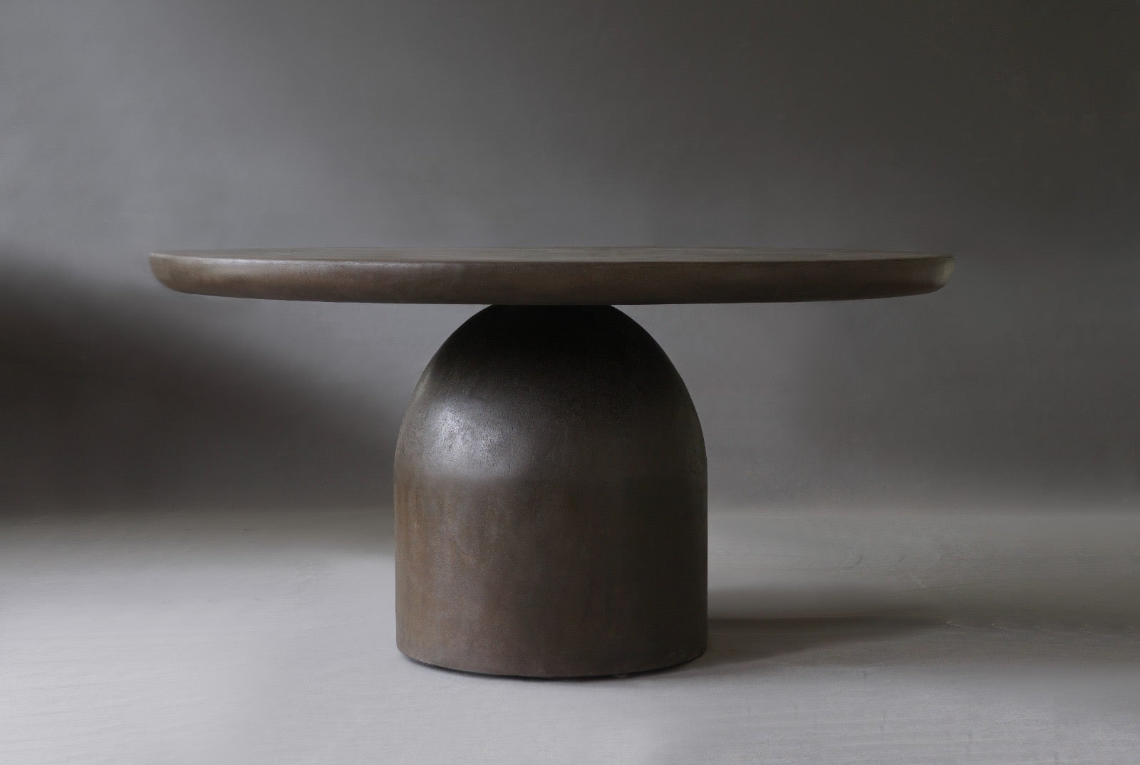 Nexus Round Dining Table in Pebble micro cement finish, showcasing its sleek design and smooth texture.