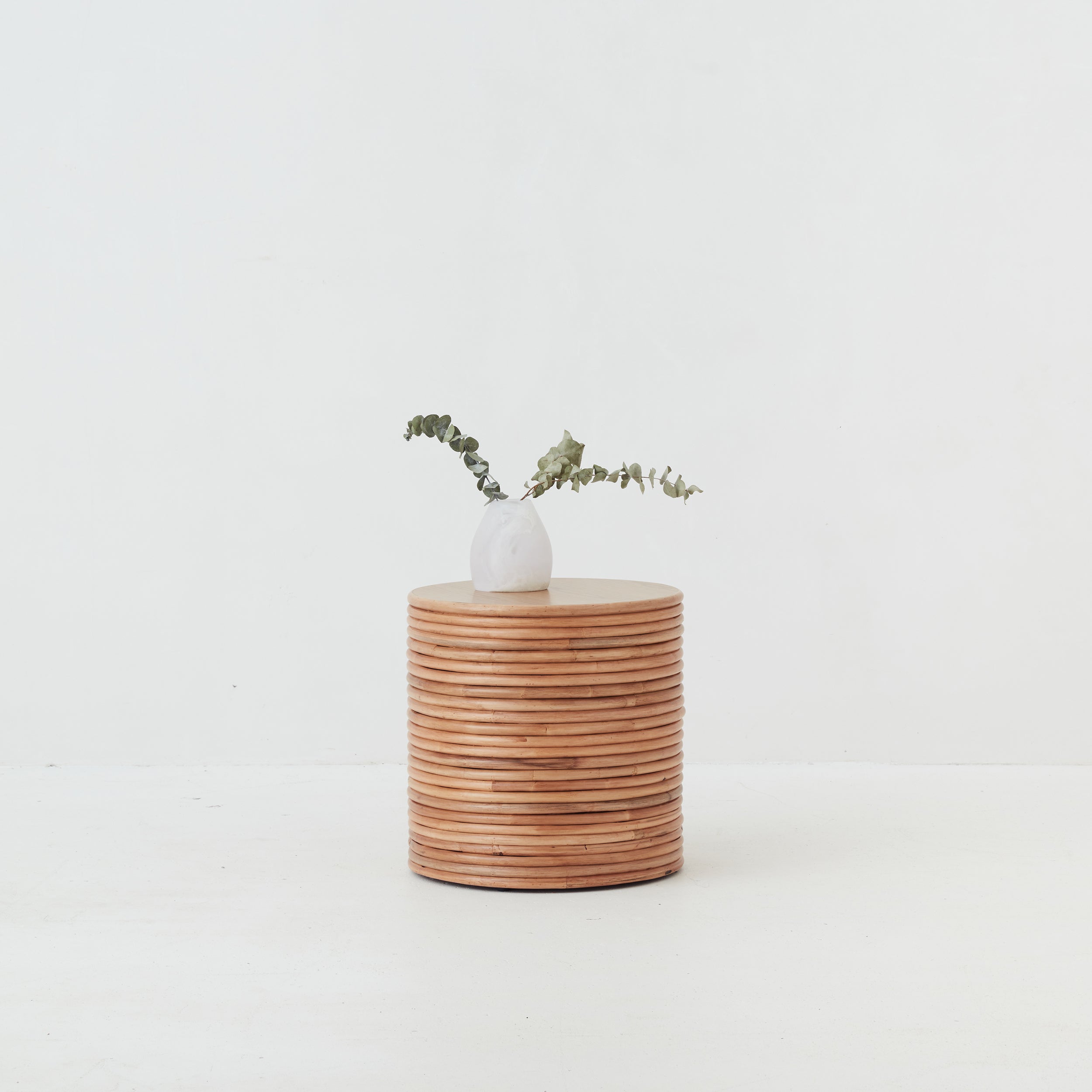 Front view of the Palma Rattan Round Side Table with natural finish and sculptural coiled design