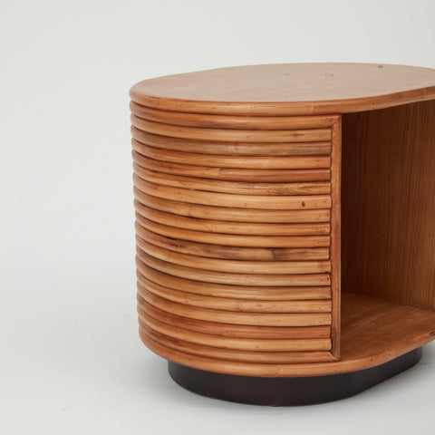 Close-up of Panama side table handcrafted in rattan with ribbed exterior and inset storage nook.