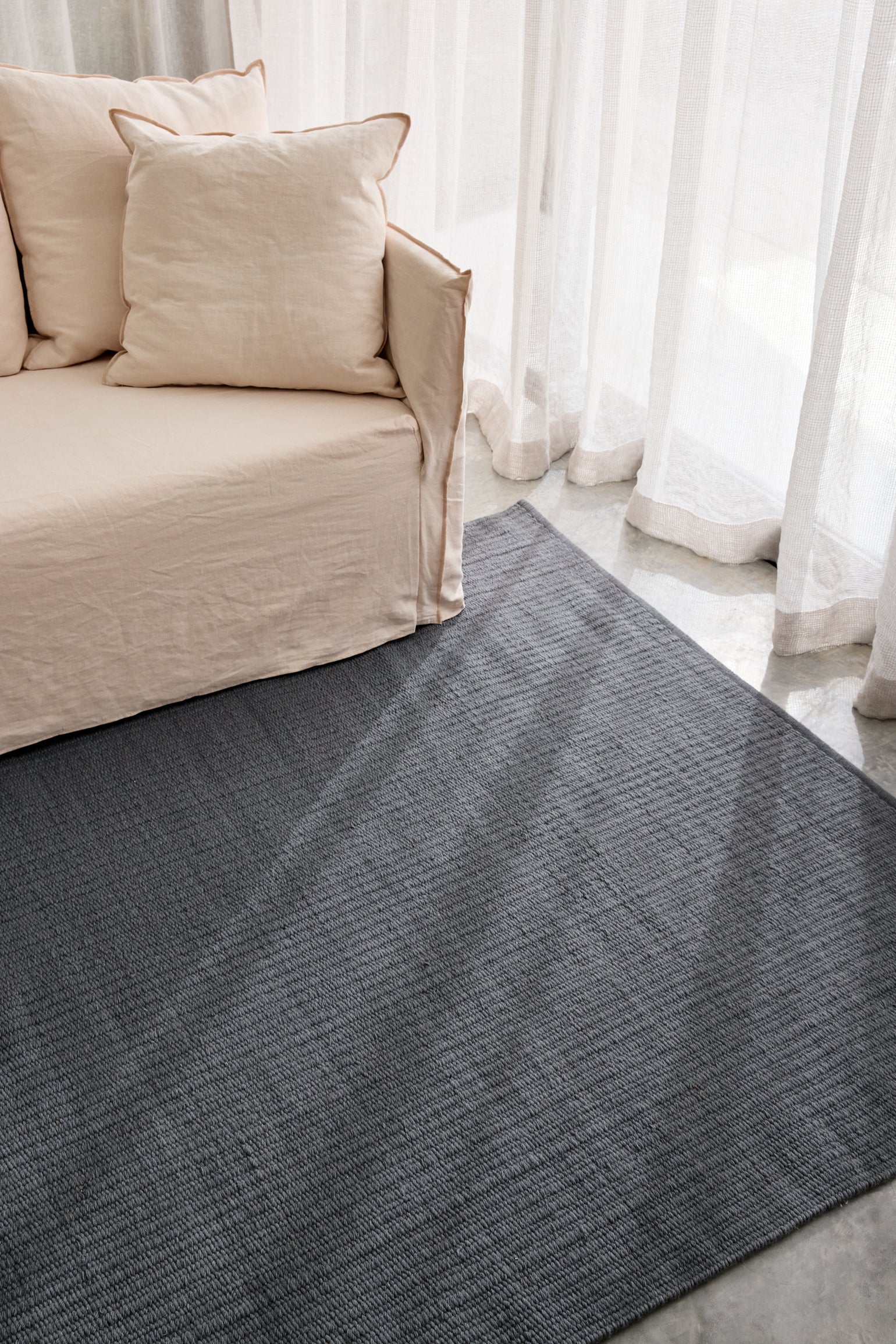 Pebble Flatweave Rug in Anthracite Grey under a sofa