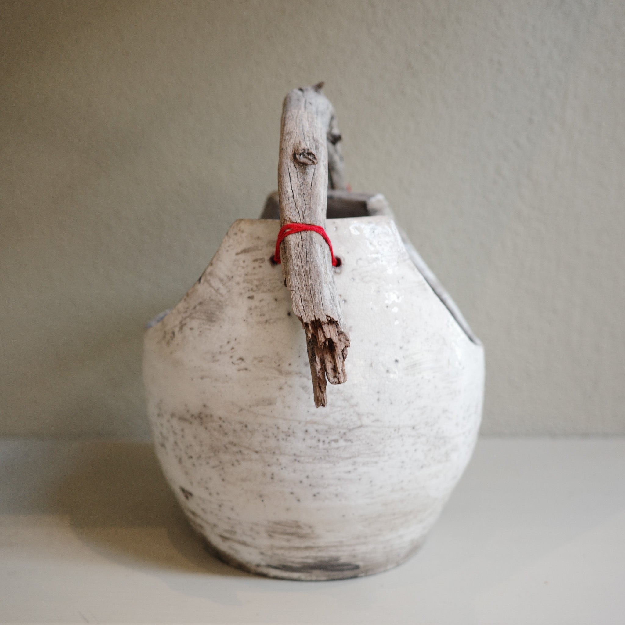 Artisan Raku pottery vase with organic driftwood handle – side angle