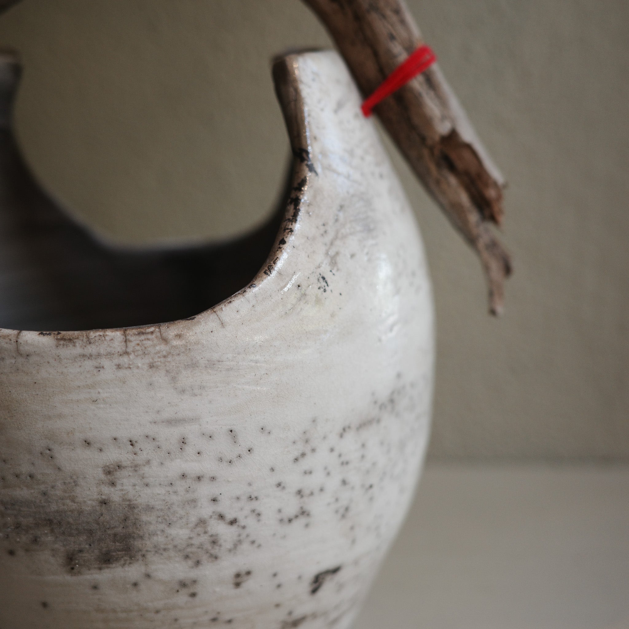 Close-up of handcrafted Raku ceramic vase with rustic wood handle