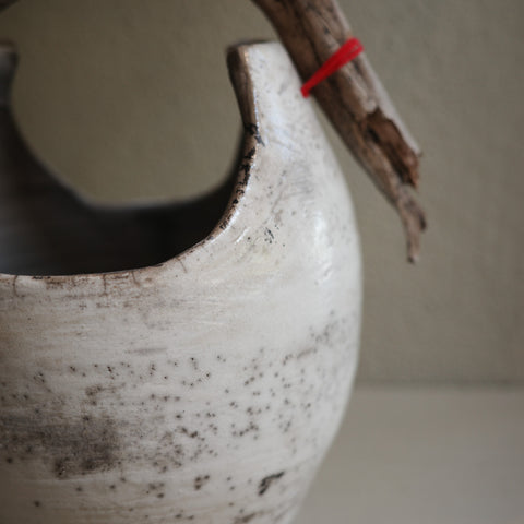 Close-up of handcrafted Raku ceramic vase with rustic wood handle