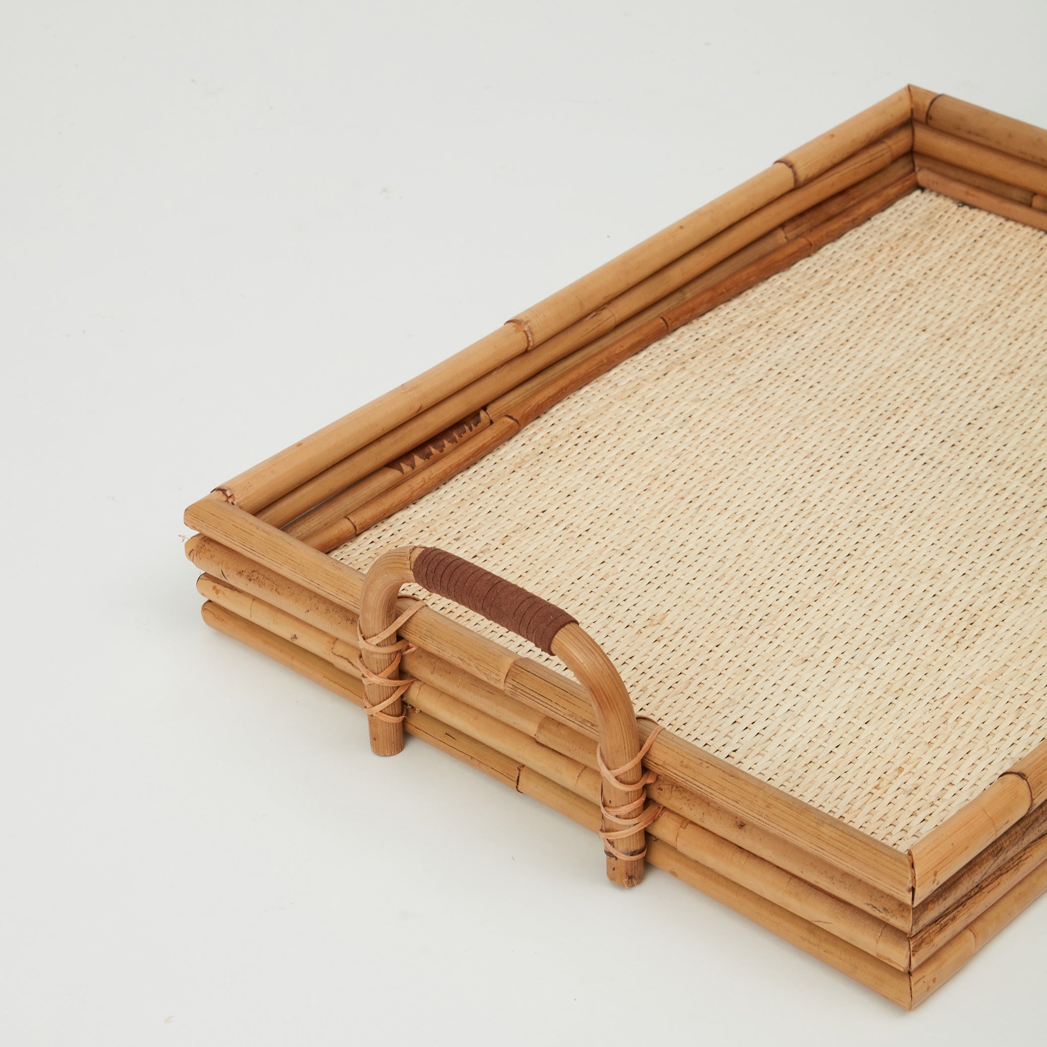 Rectangular Cuba tray handcrafted in natural rattan with raised edges, side view.