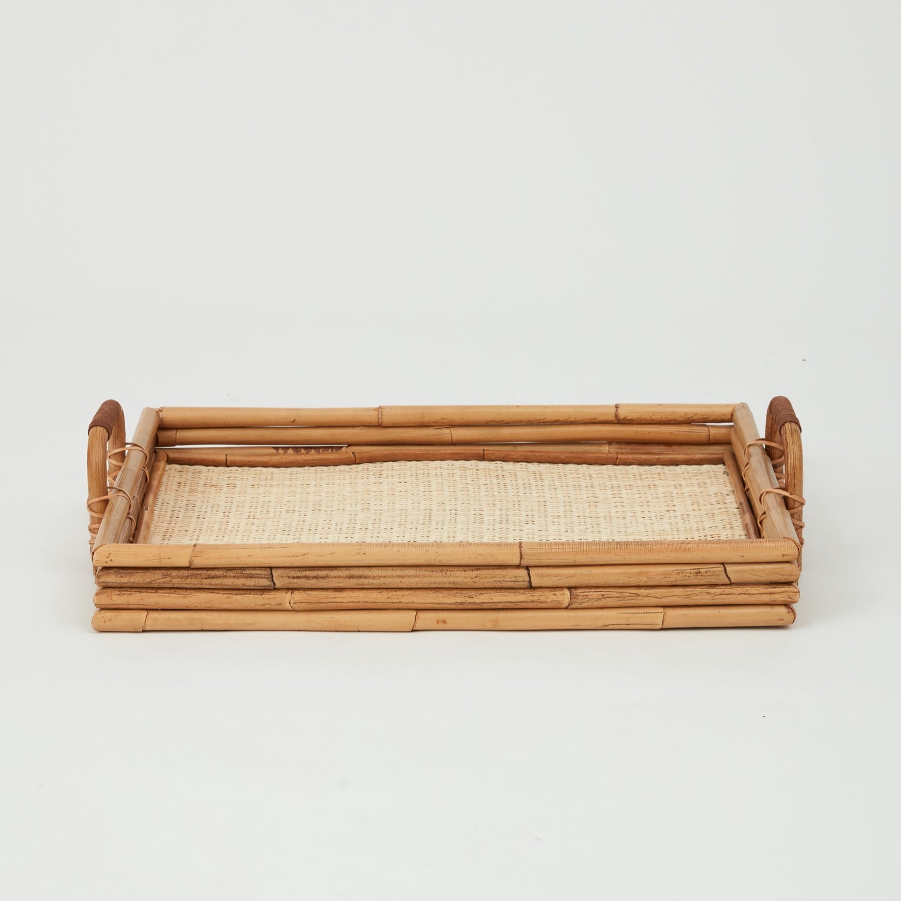 Cuba rectangular serving tray in natural rattan, woven base with raised edges, top view.