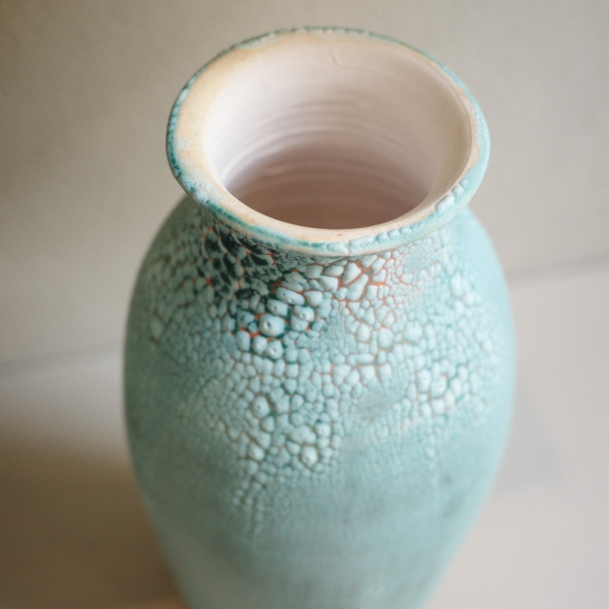 Detail of handmade tall green ceramic vase with crawl glaze texture, created by Australian ceramicist Jacqui Sosnowski.